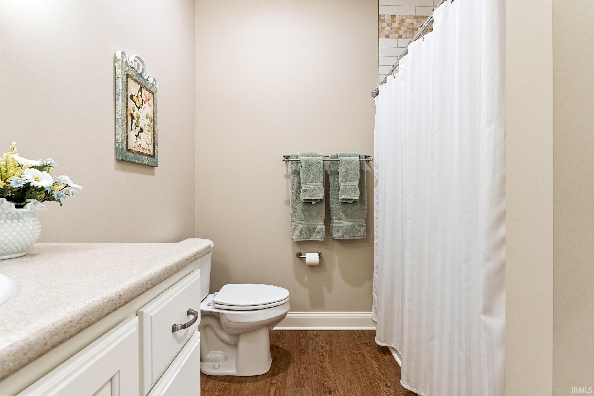 Full bath featuring vanity, a shower with curtain, and dark wood-style flooring