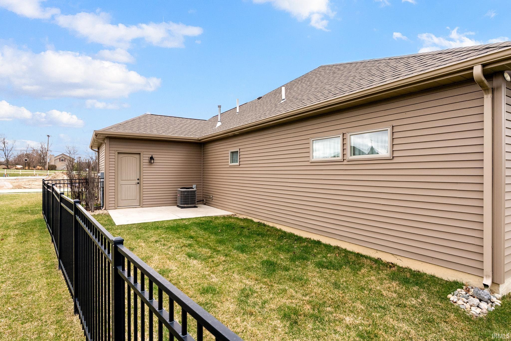 View of side of property with a patio and a shingled roof
