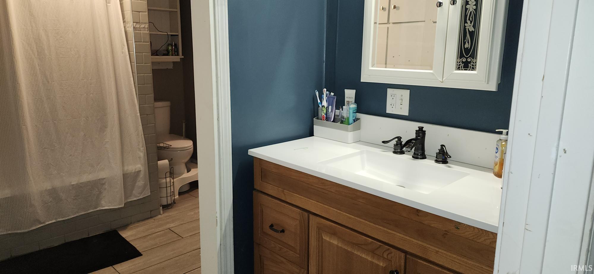 Full bath featuring vanity, wood finish floors, and shower / bath combination with curtain