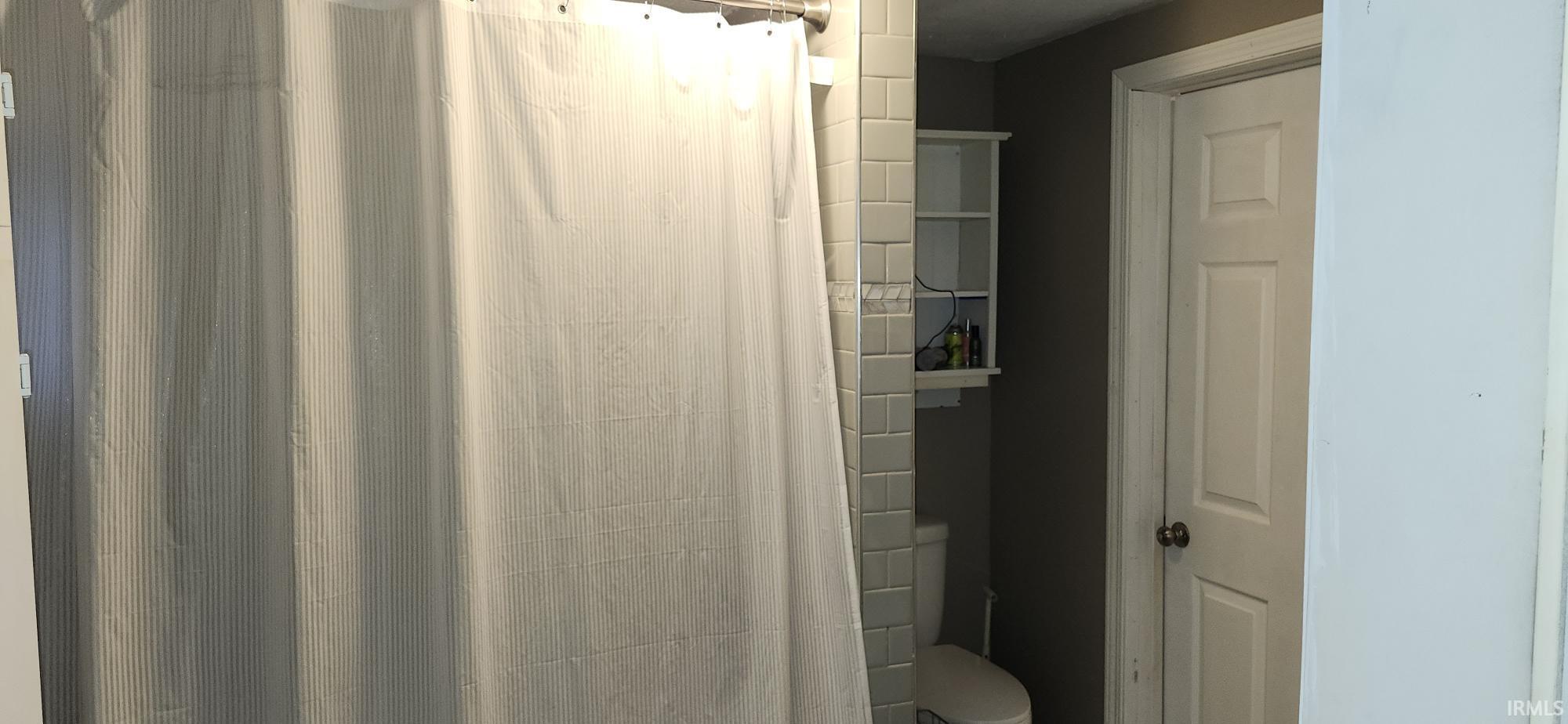 Full bathroom featuring curtained shower and toilet