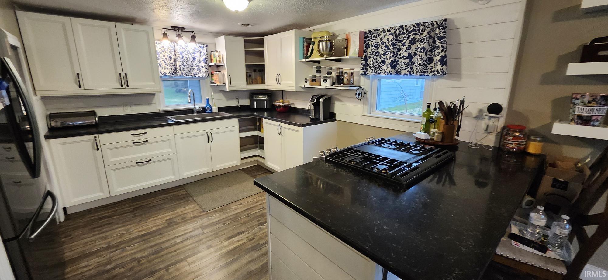 Kitchen featuring dark countertops, freestanding refrigerator, plenty of natural light, white cabinets, and a textured ceiling