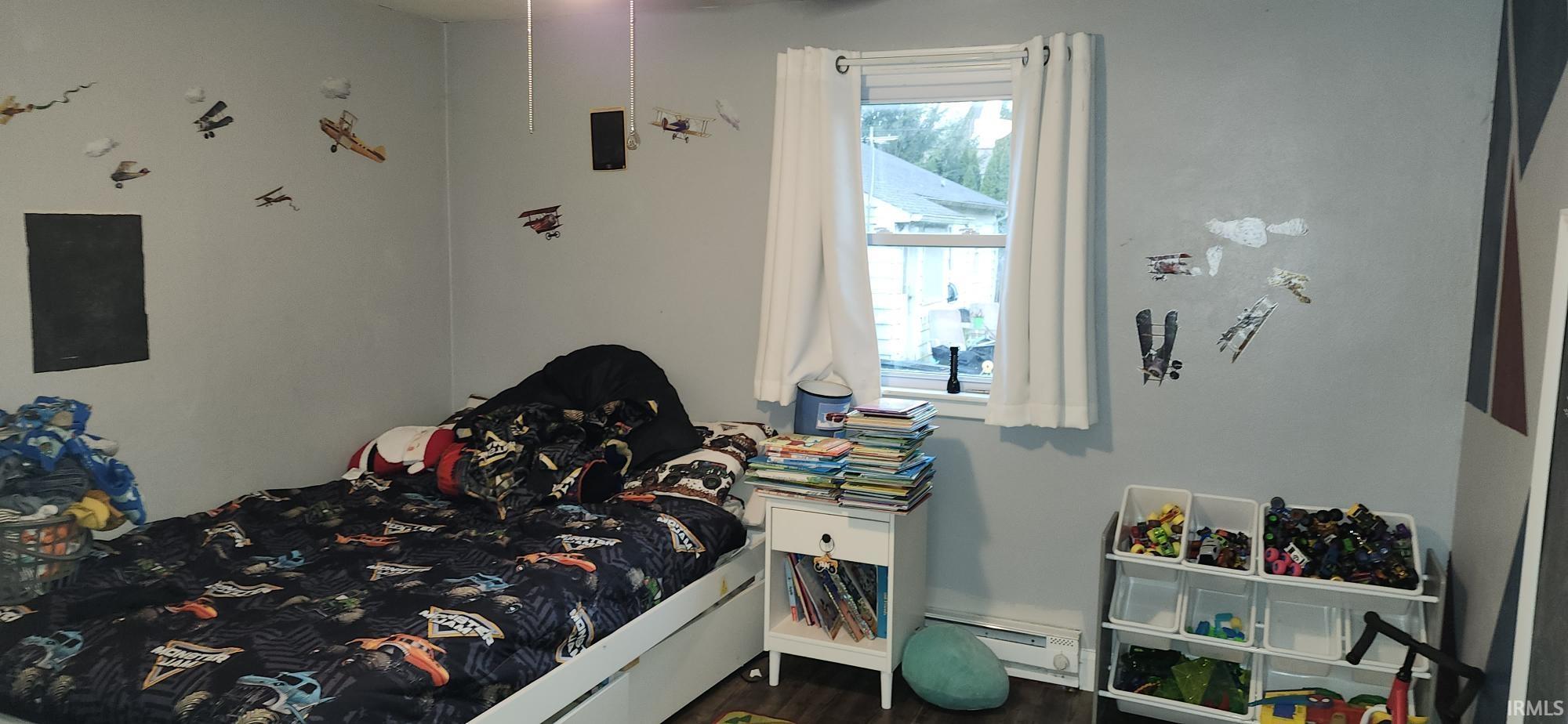 Bedroom with baseboard heating and dark wood finished floors
