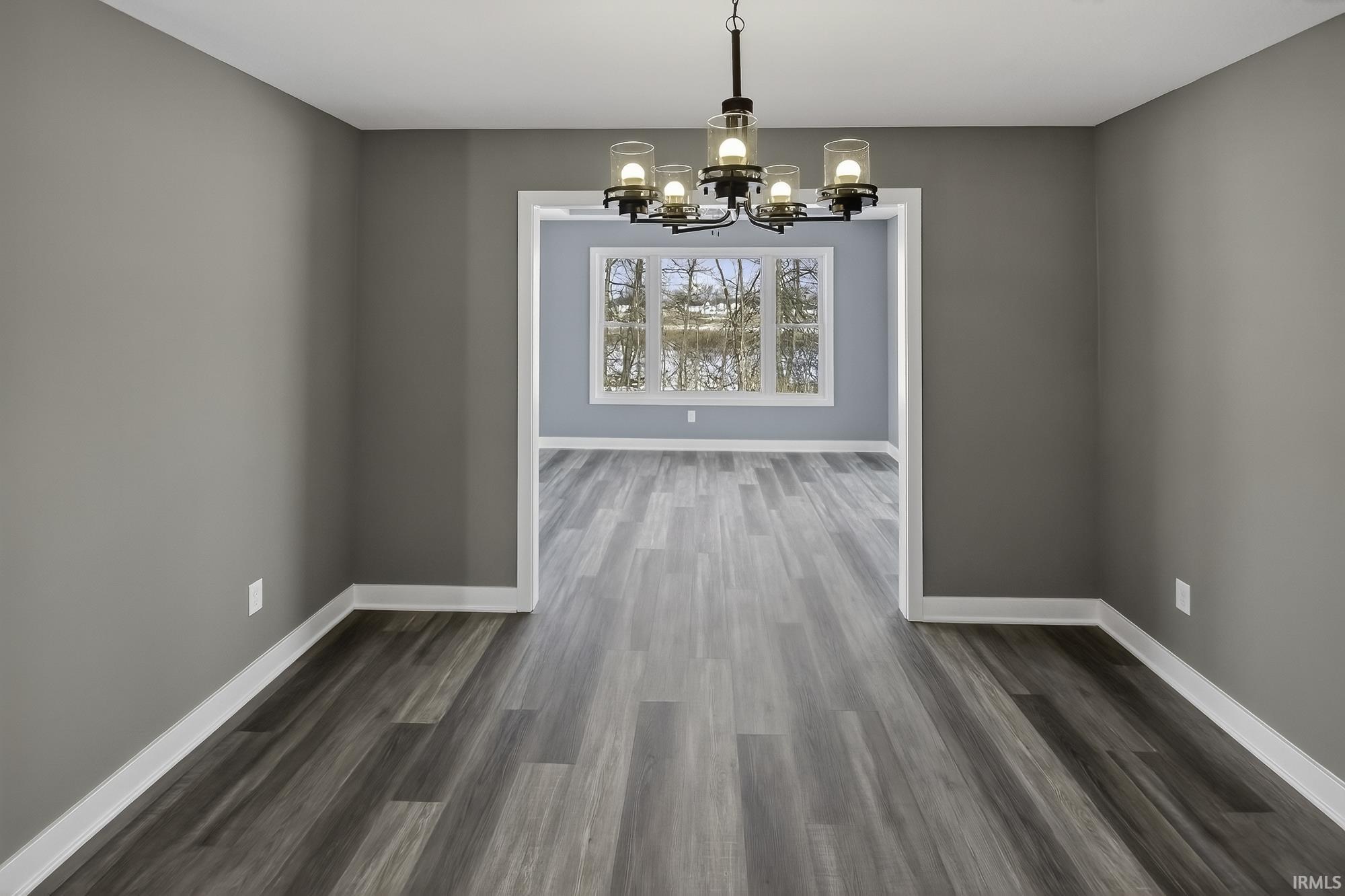 Unfurnished dining area with hanging lights and dark wood-style floors