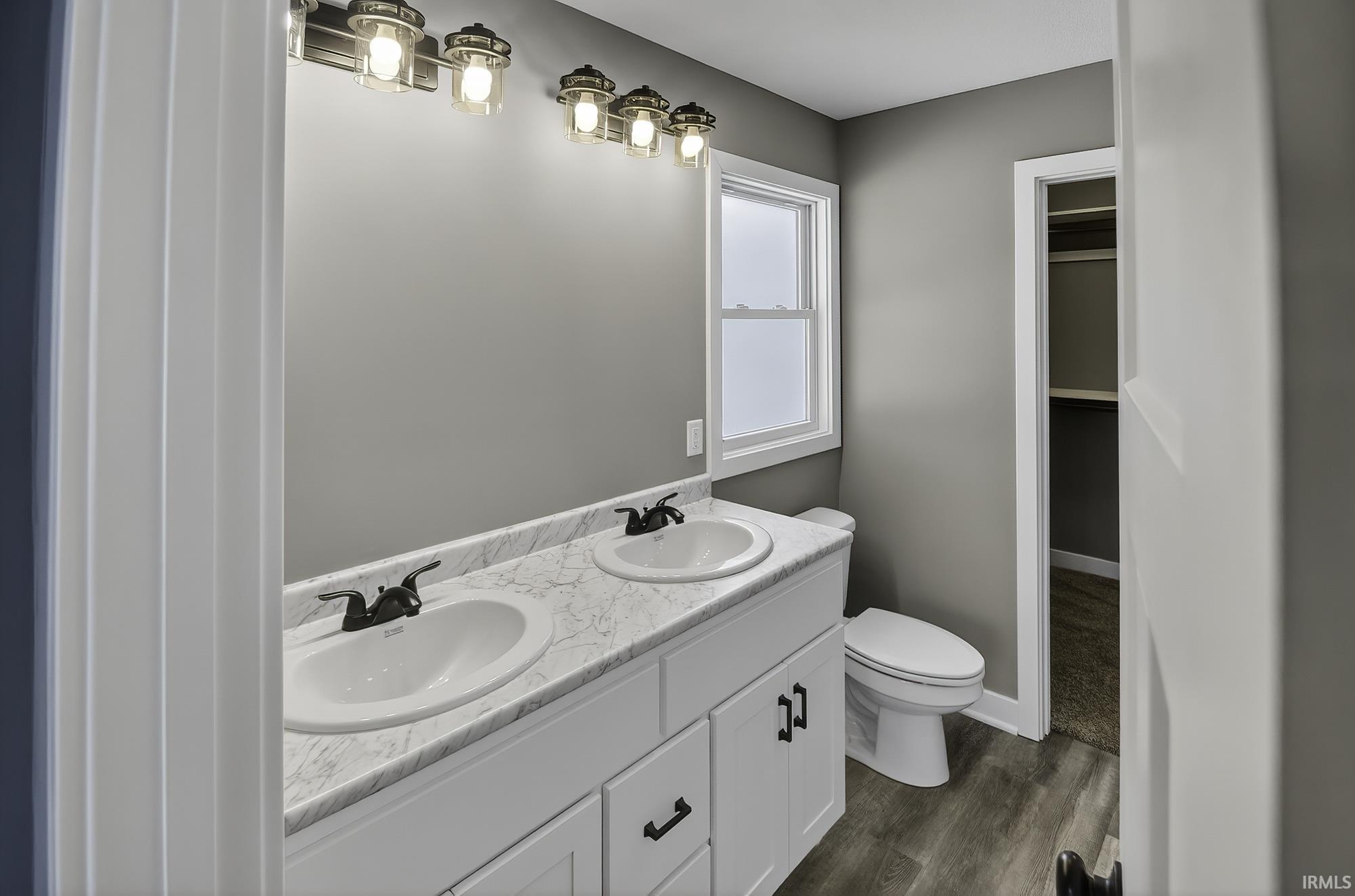 Bathroom with double vanity and dark wood finished floors