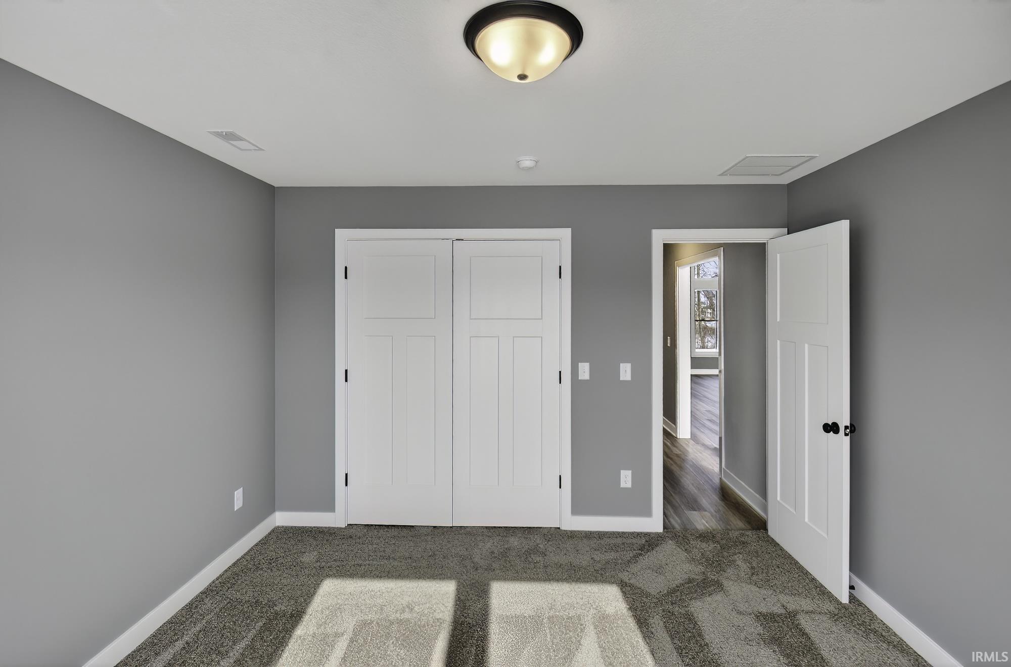 Unfurnished bedroom featuring a closet and dark carpet