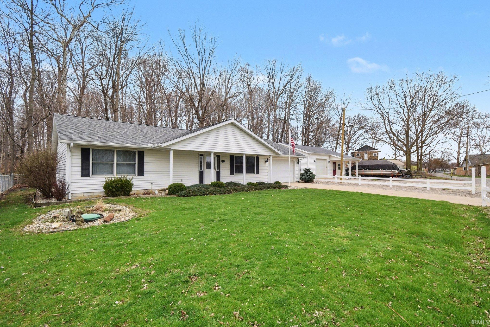 Single story home with a garage, concrete driveway, a porch, and roof with shingles