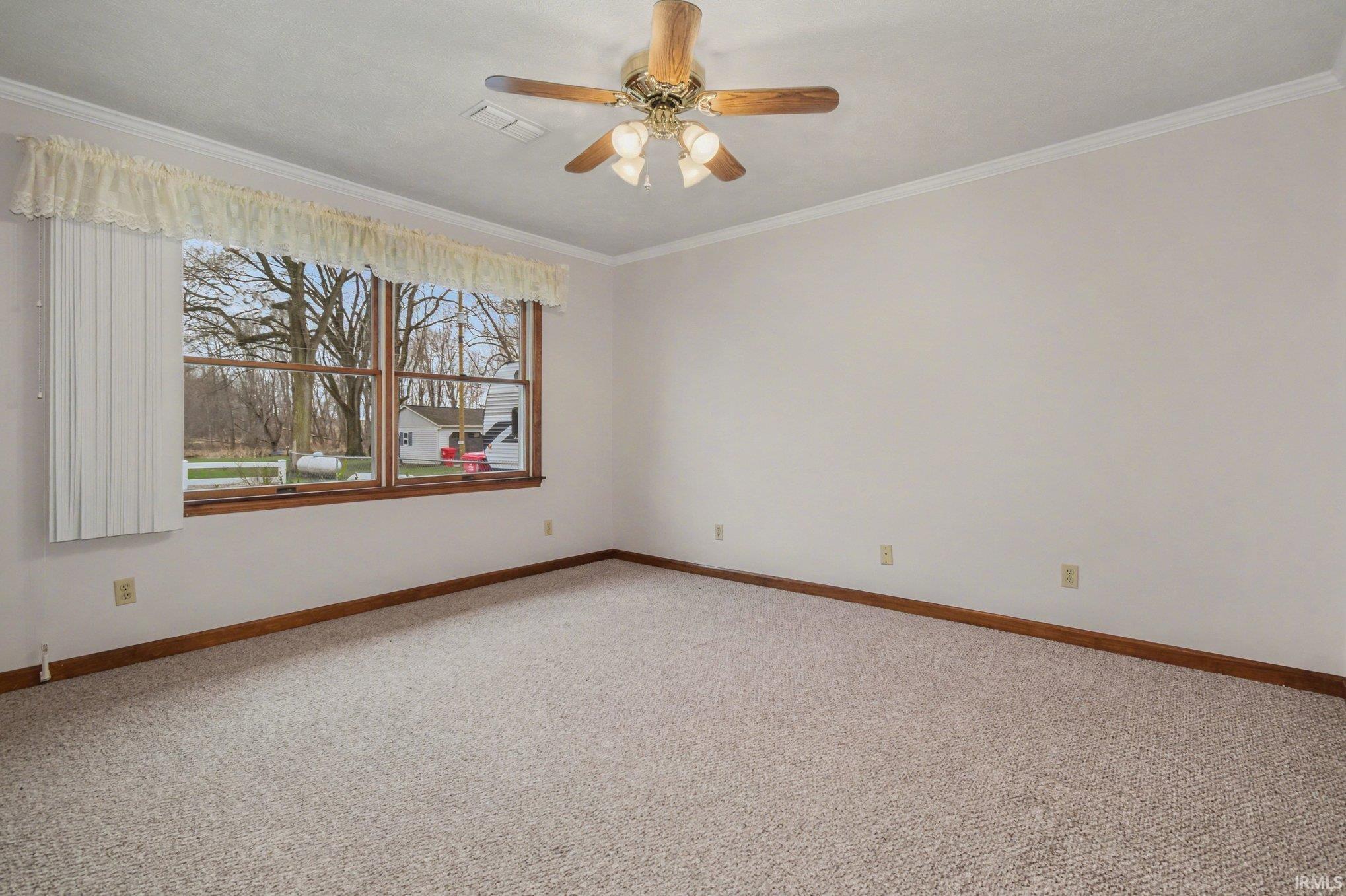 Unfurnished room featuring light carpet, ornamental molding, and ceiling fan