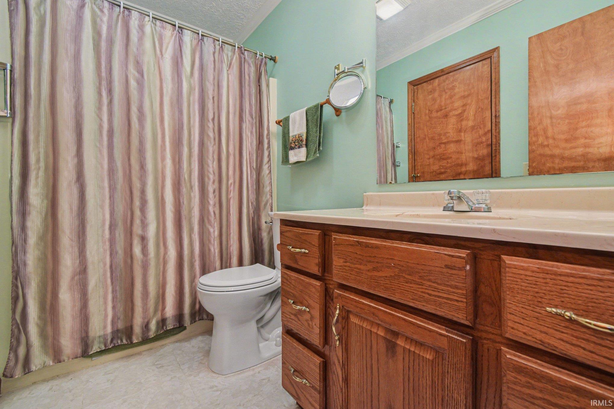 Full bath with vanity, a shower with curtain, and a textured ceiling