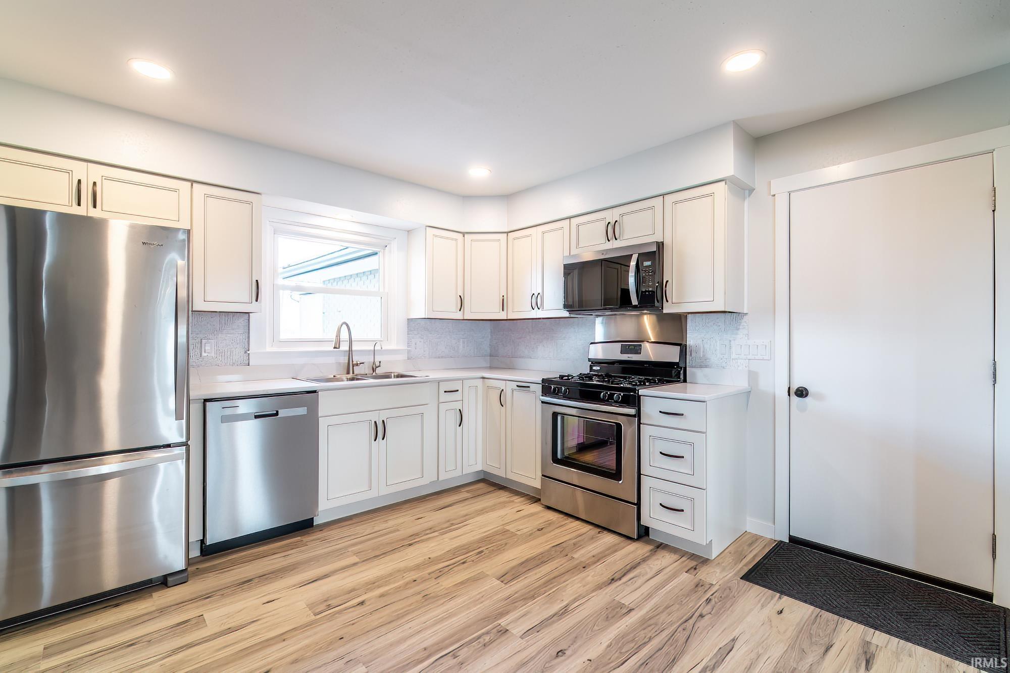 Kitchen featuring stainless steel appliances, light countertops, light wood-type flooring, tasteful backsplash, and recessed lighting