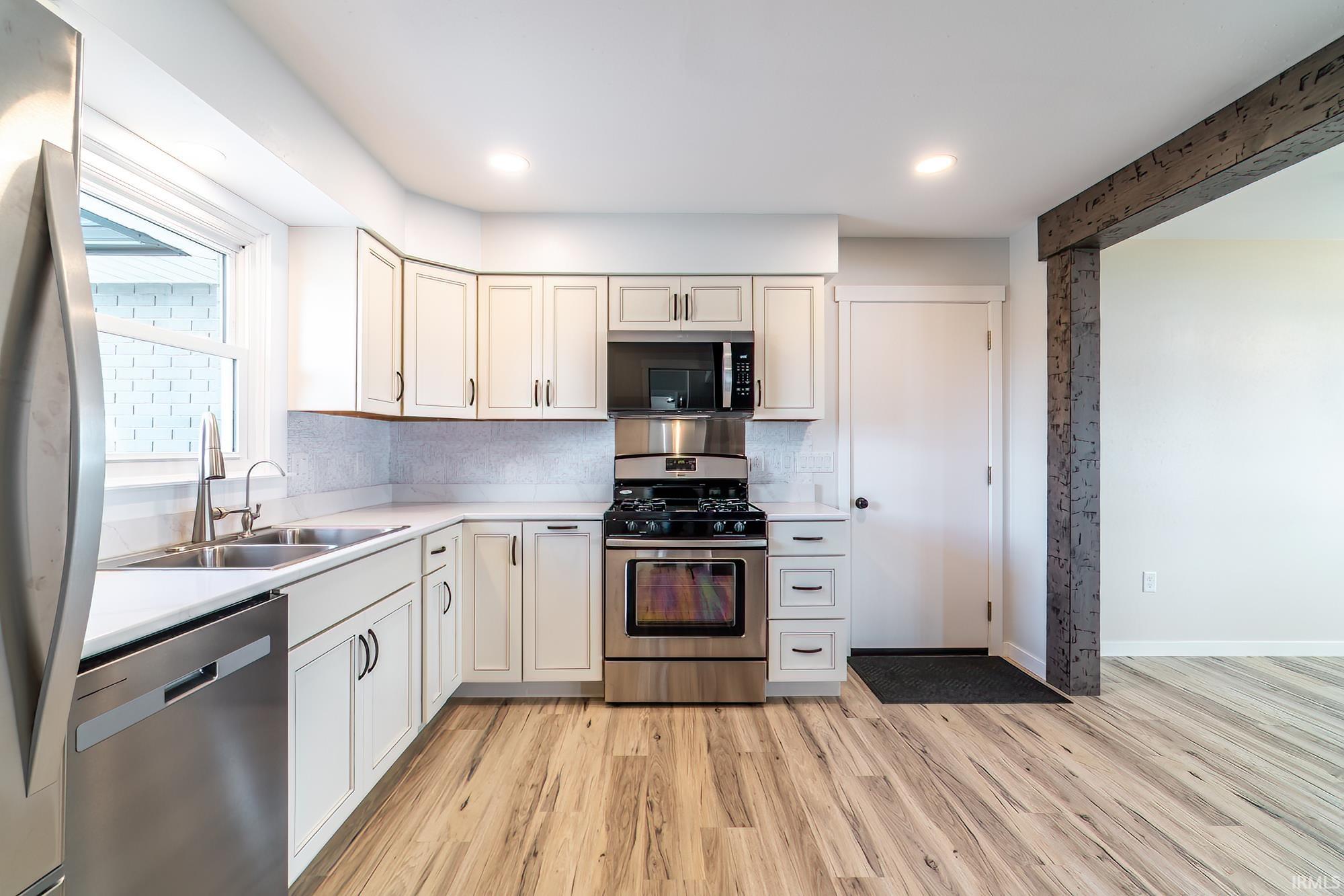 Kitchen with stainless steel appliances, light countertops, light wood-type flooring, tasteful backsplash, and recessed lighting