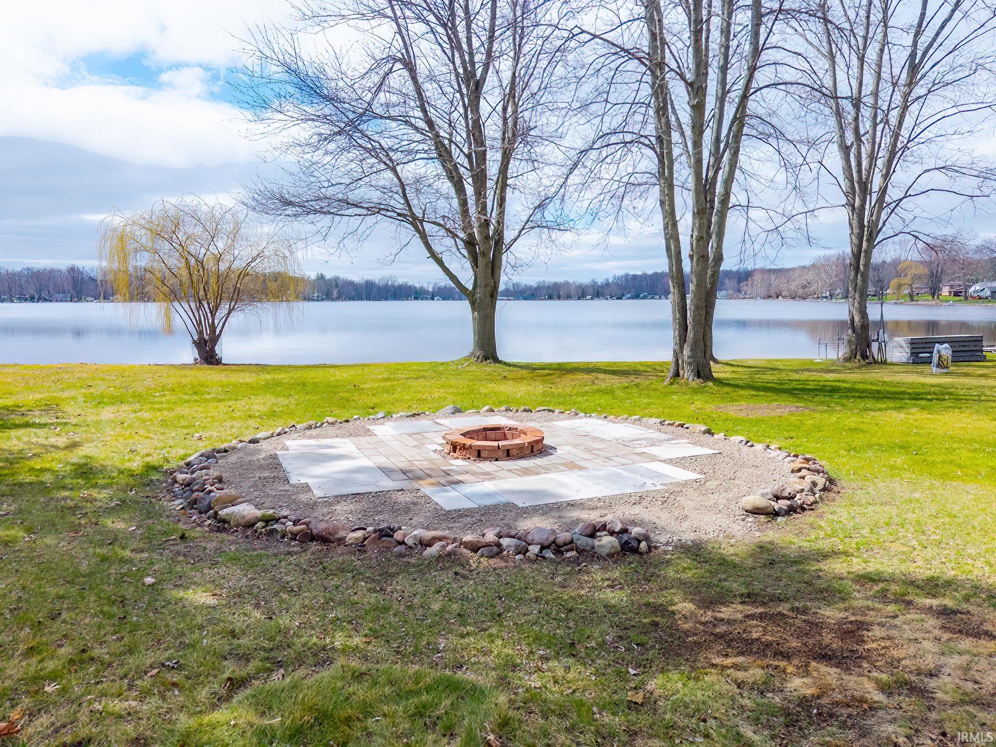 View of green lawn with an outdoor fire pit and a water view