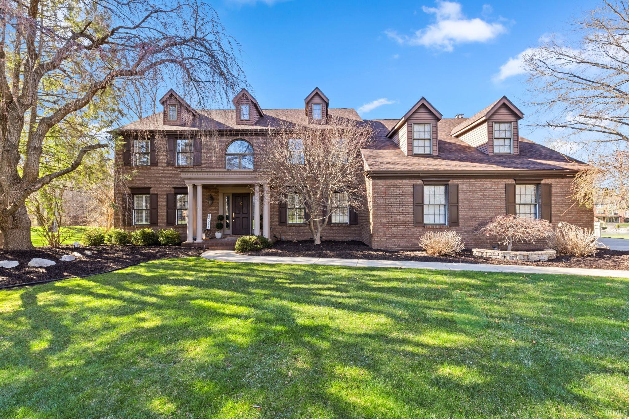 Colonial house featuring brick siding, a front yard, and a porch