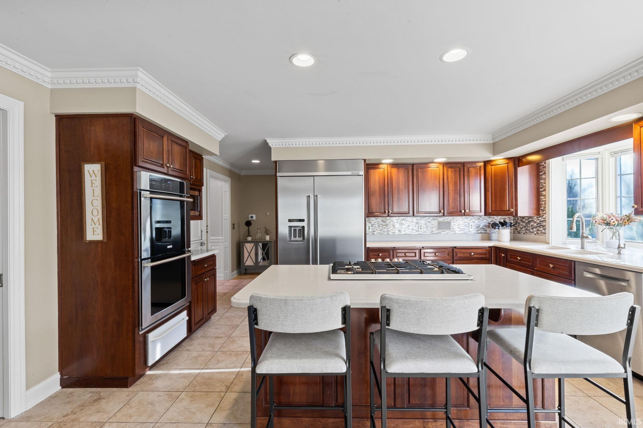 Kitchen featuring a center island, a breakfast bar area, stainless steel appliances, ornamental molding, and light tile patterned flooring