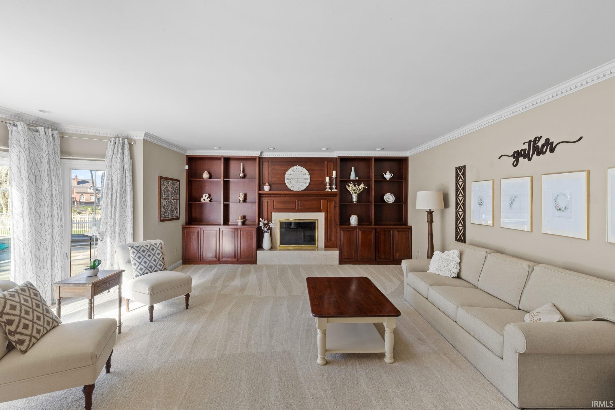 Living room featuring a glass covered fireplace, crown molding, and light carpet