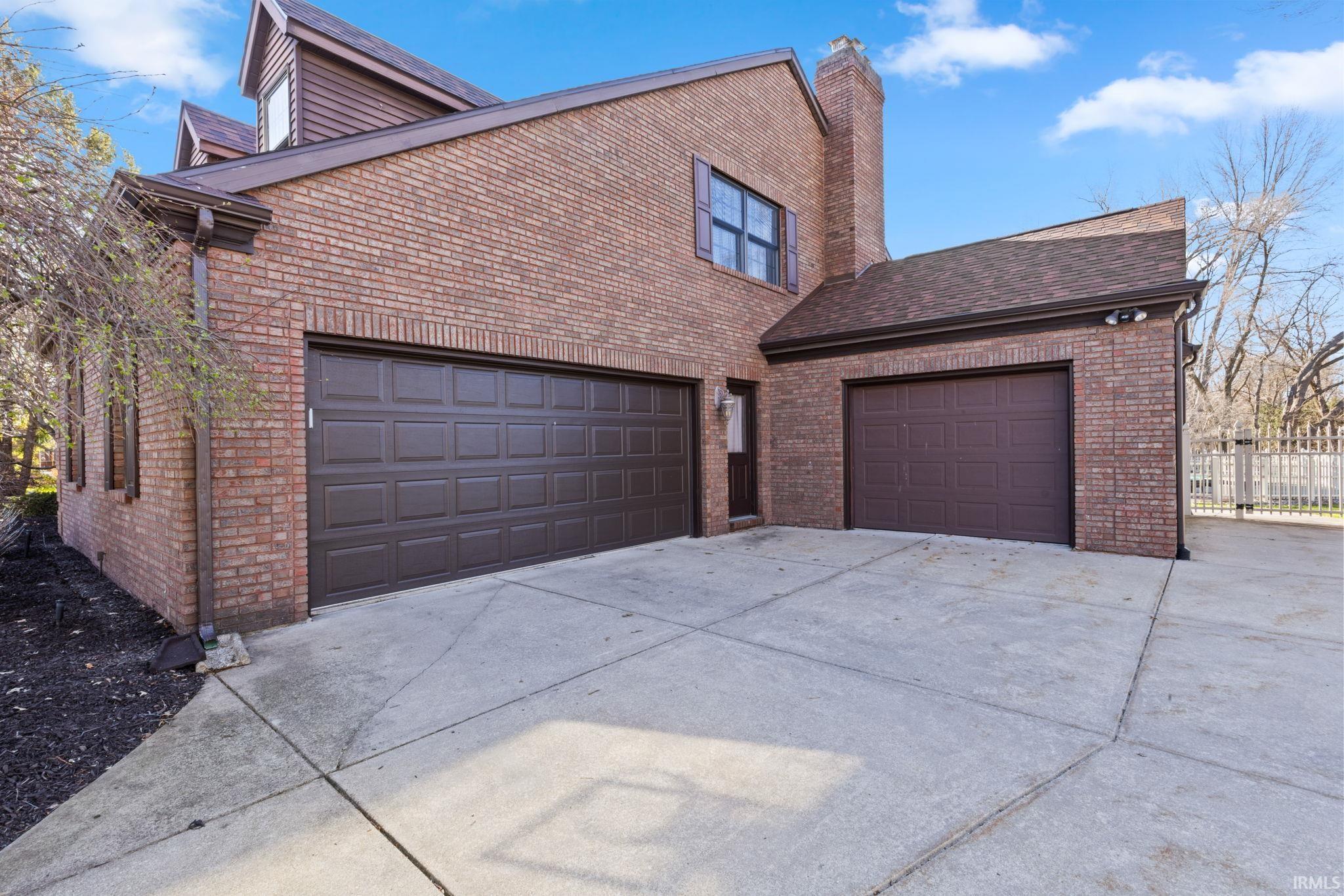 View of home's exterior with brick siding, driveway, a garage, a chimney, and roof with shingles