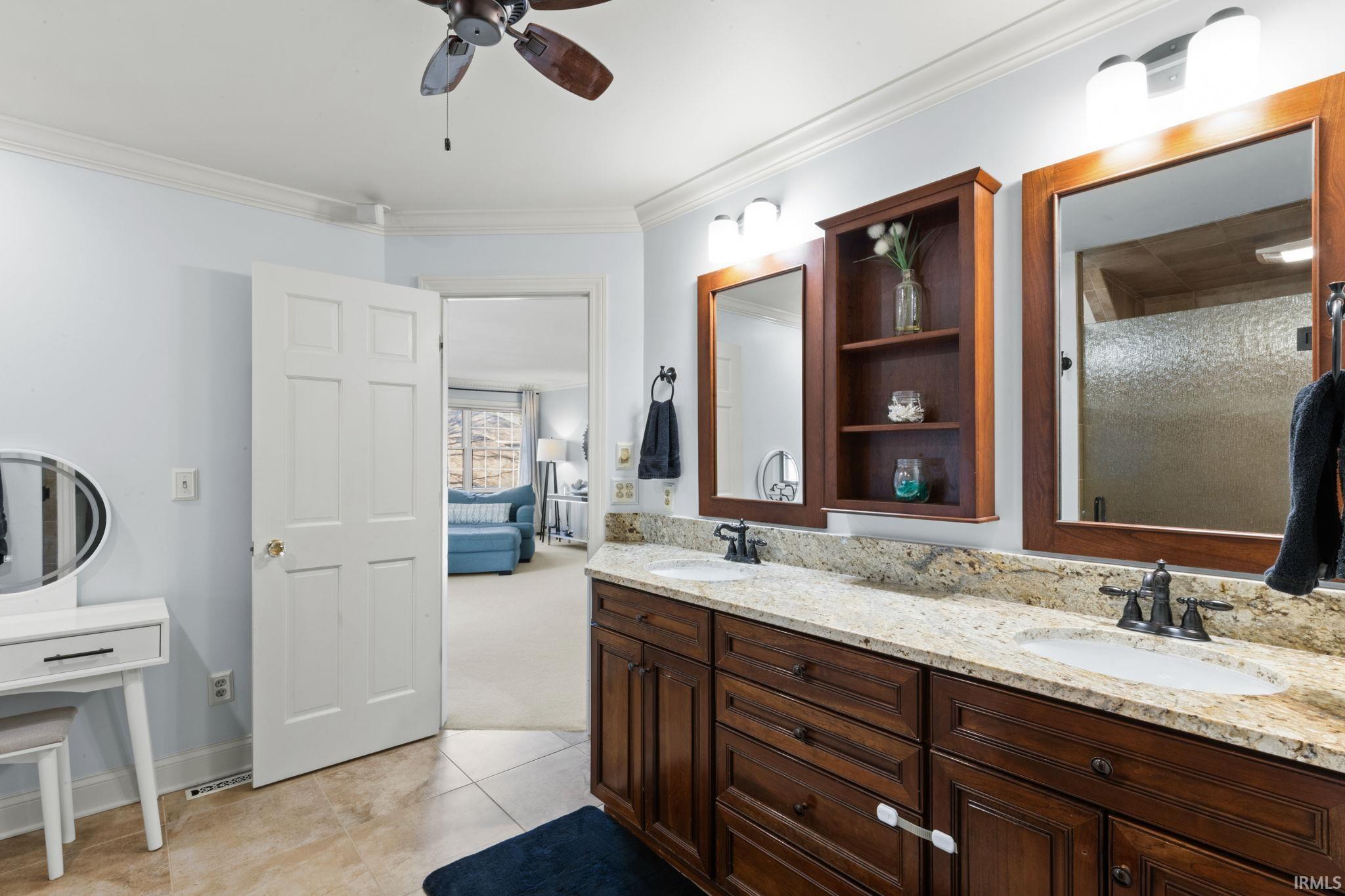 Full bathroom with double vanity, crown molding, a ceiling fan, ensuite bathroom, and light tile patterned floors