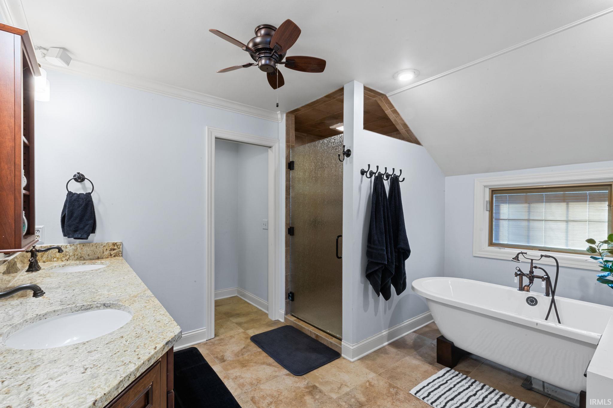 Bathroom with double vanity, a freestanding bath, a shower stall, lofted ceiling, and a ceiling fan