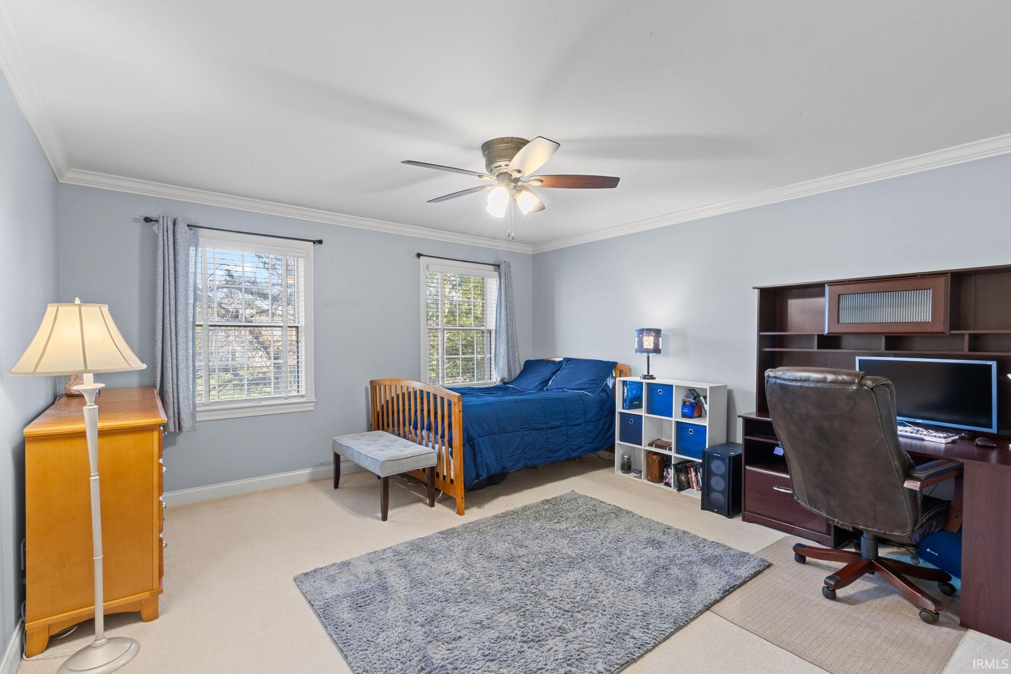 Bedroom featuring an office area, crown molding, a ceiling fan, and light colored carpet