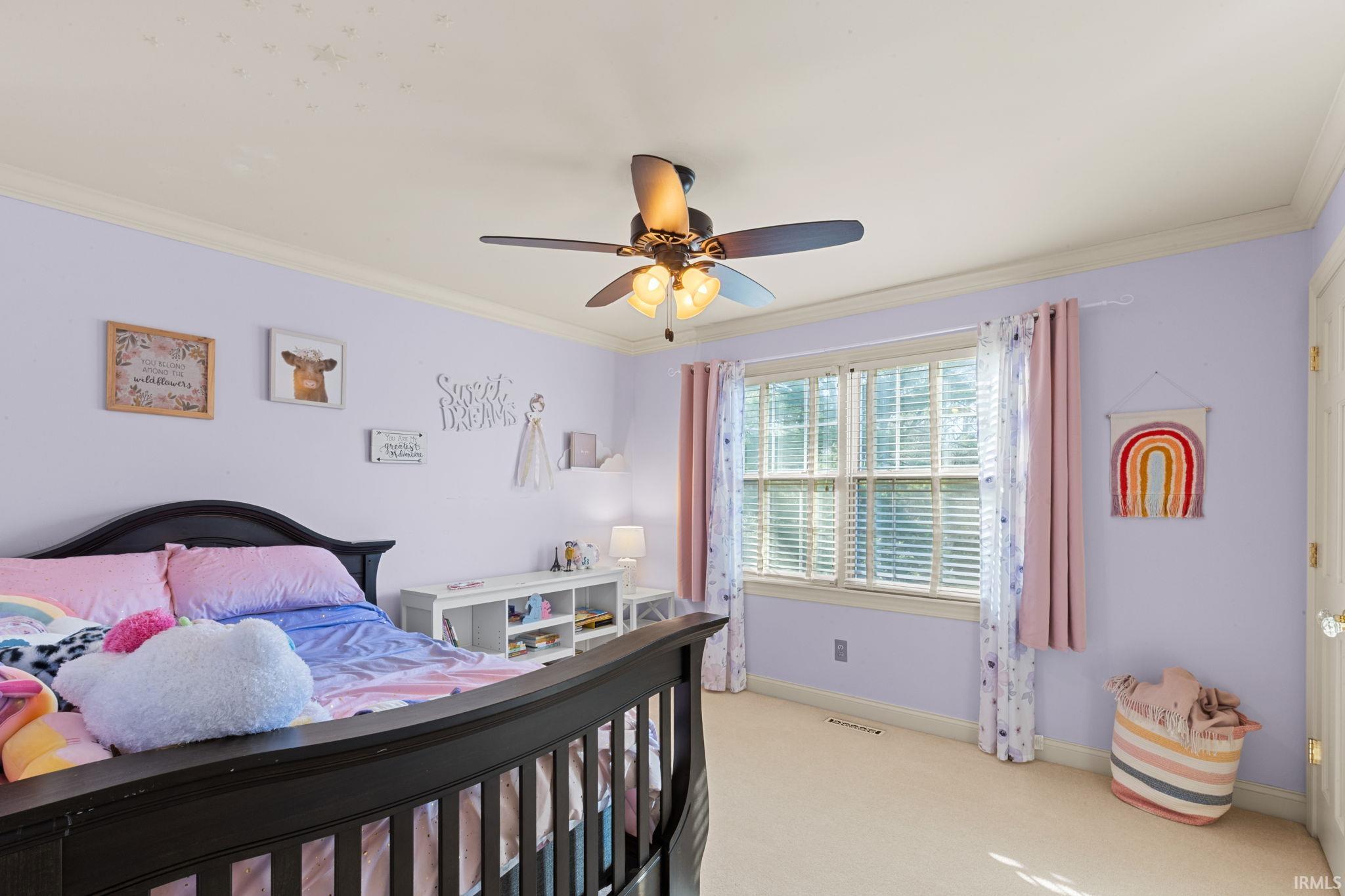 Bedroom with a ceiling fan, crown molding, and light carpet