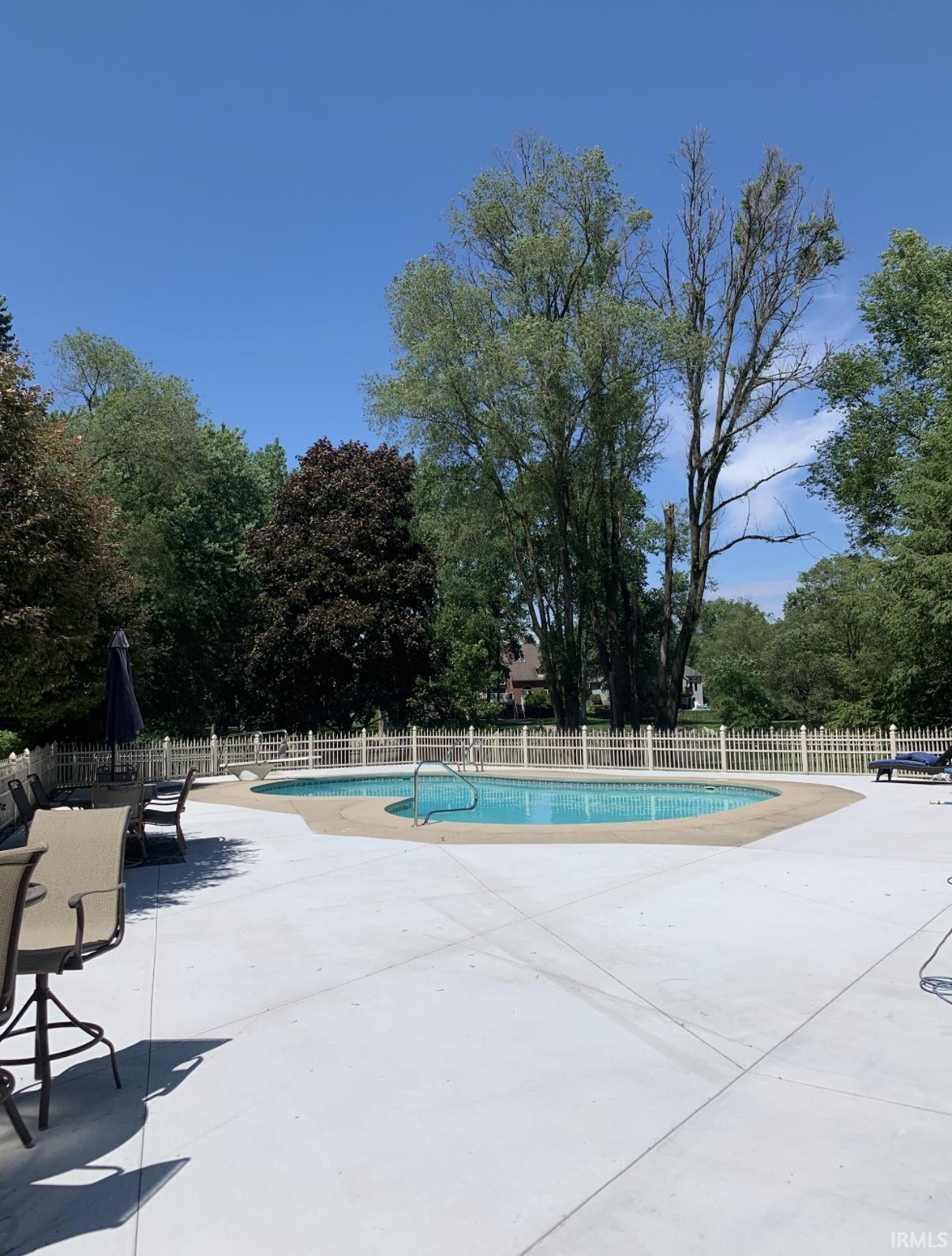 Community pool featuring a patio area and view of wooded area