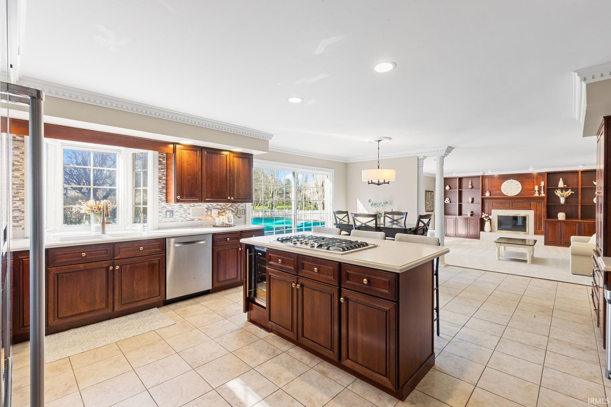 Kitchen with crown molding, hanging light fixtures, open floor plan, stainless steel appliances, and a kitchen island