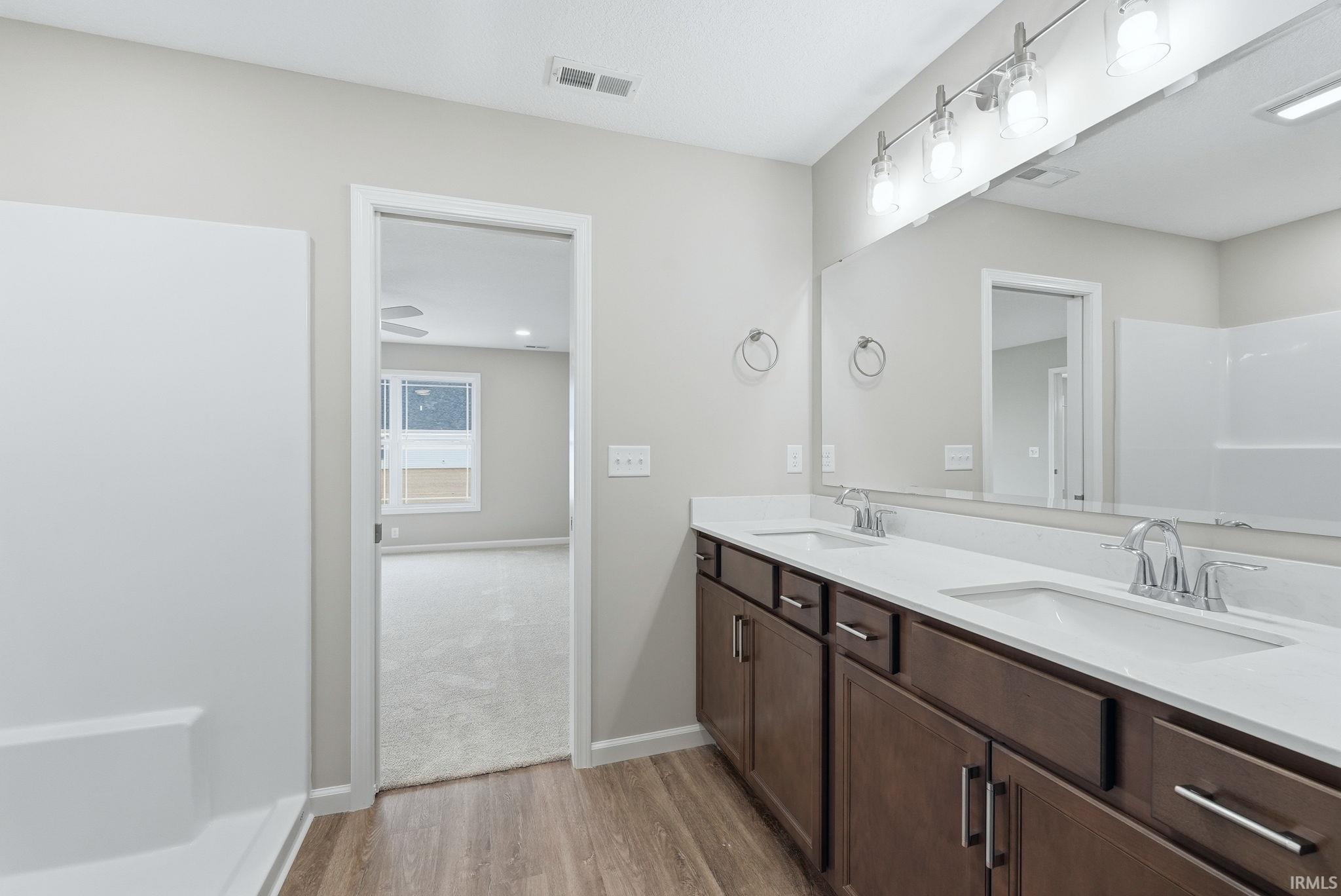 Full bathroom with double vanity and light wood-style floors