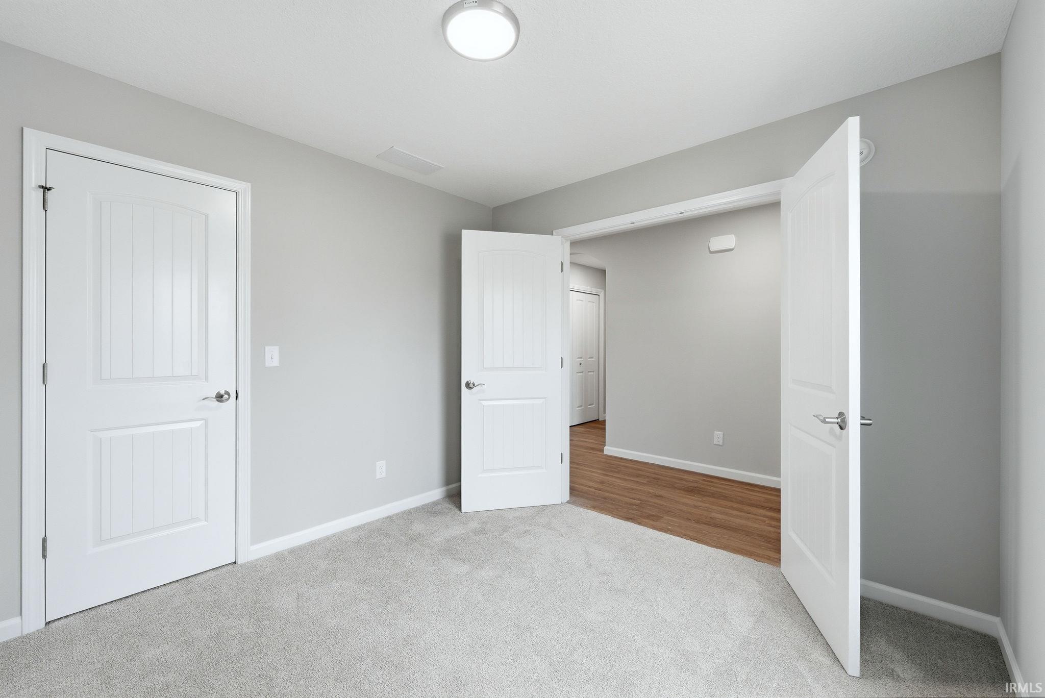 Unfurnished bedroom with light carpet and baseboards