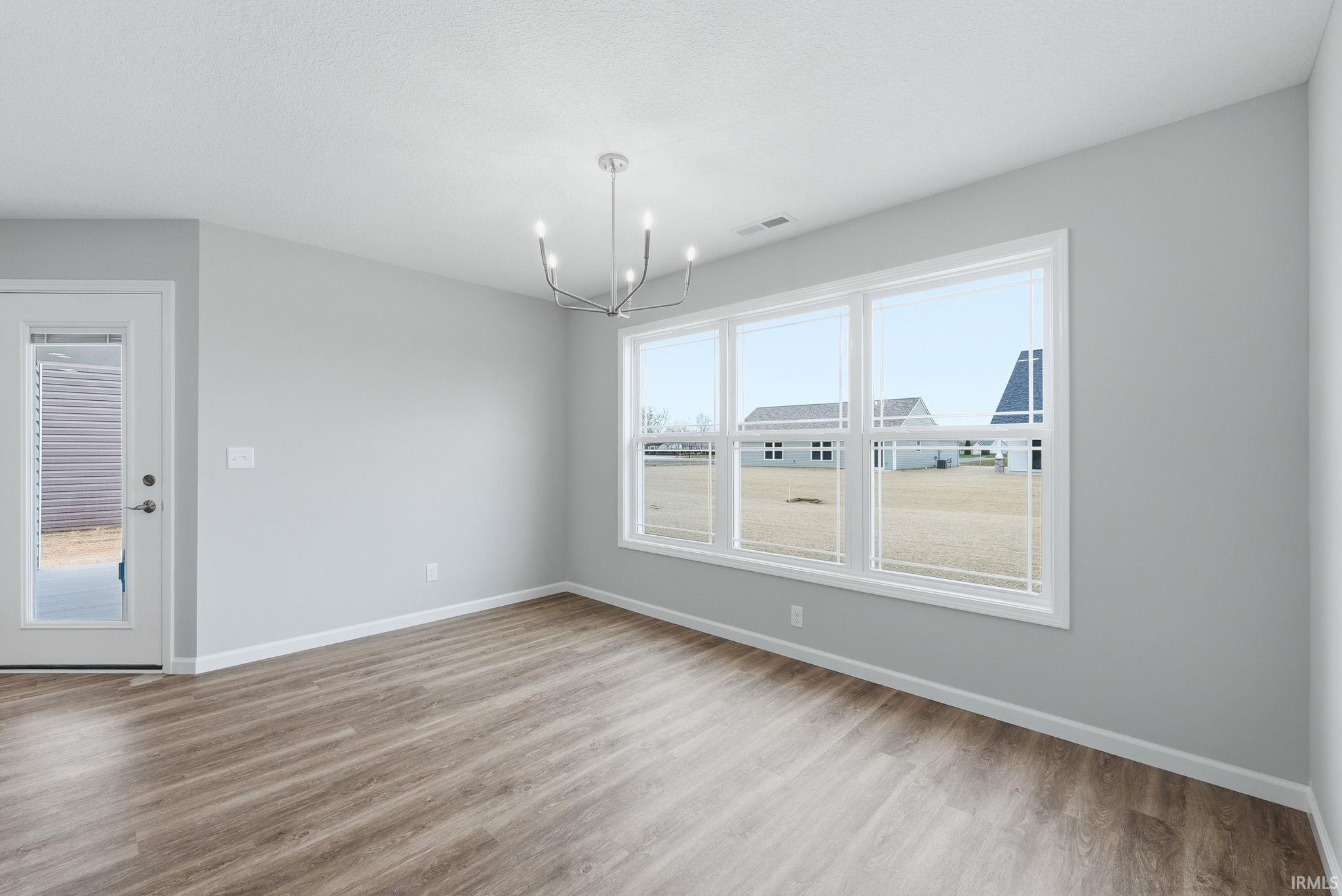 Empty room with suspended lighting and light wood finished floors