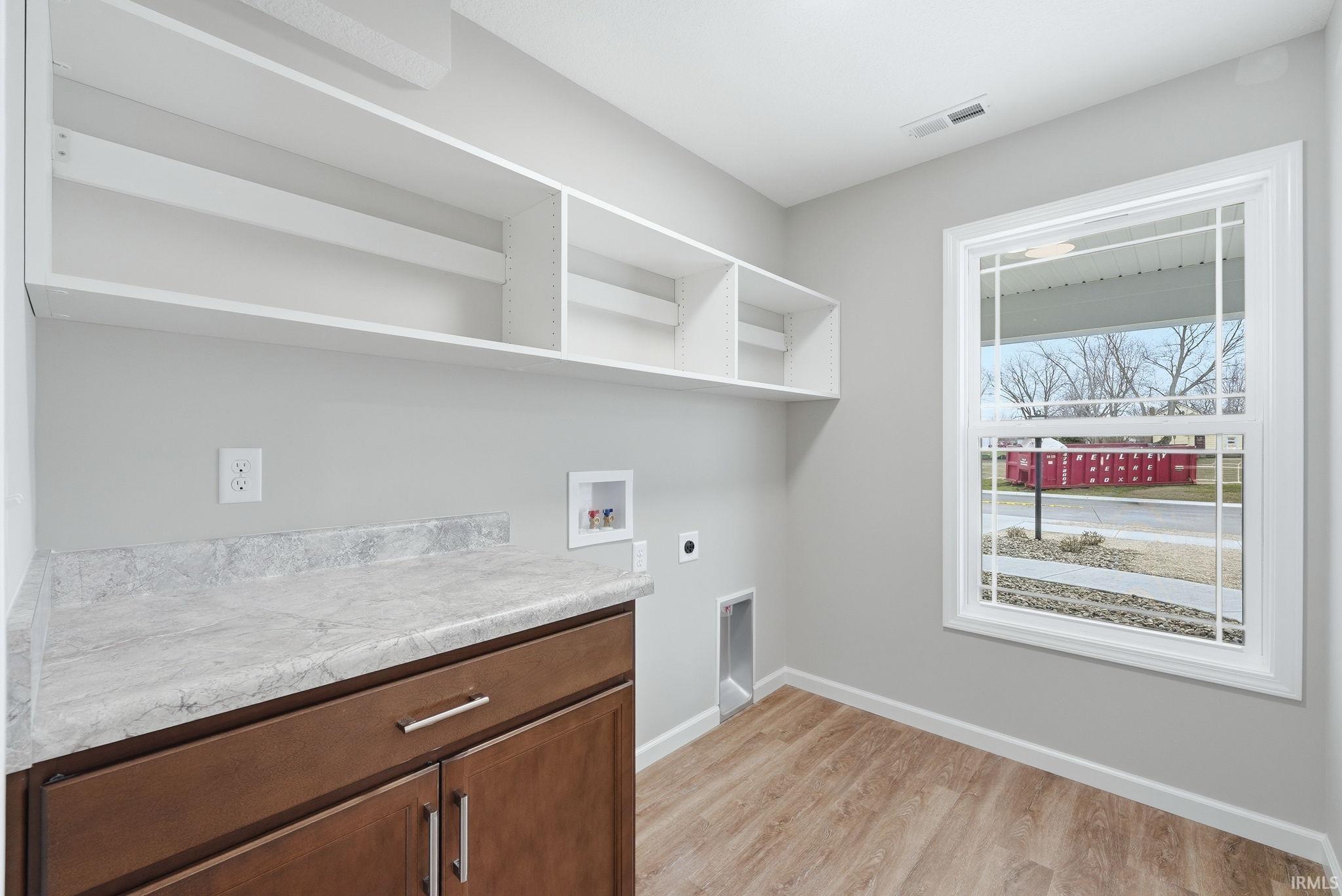 Laundry room with washer hookup, light wood-type flooring, electric dryer hookup, and cabinet space
