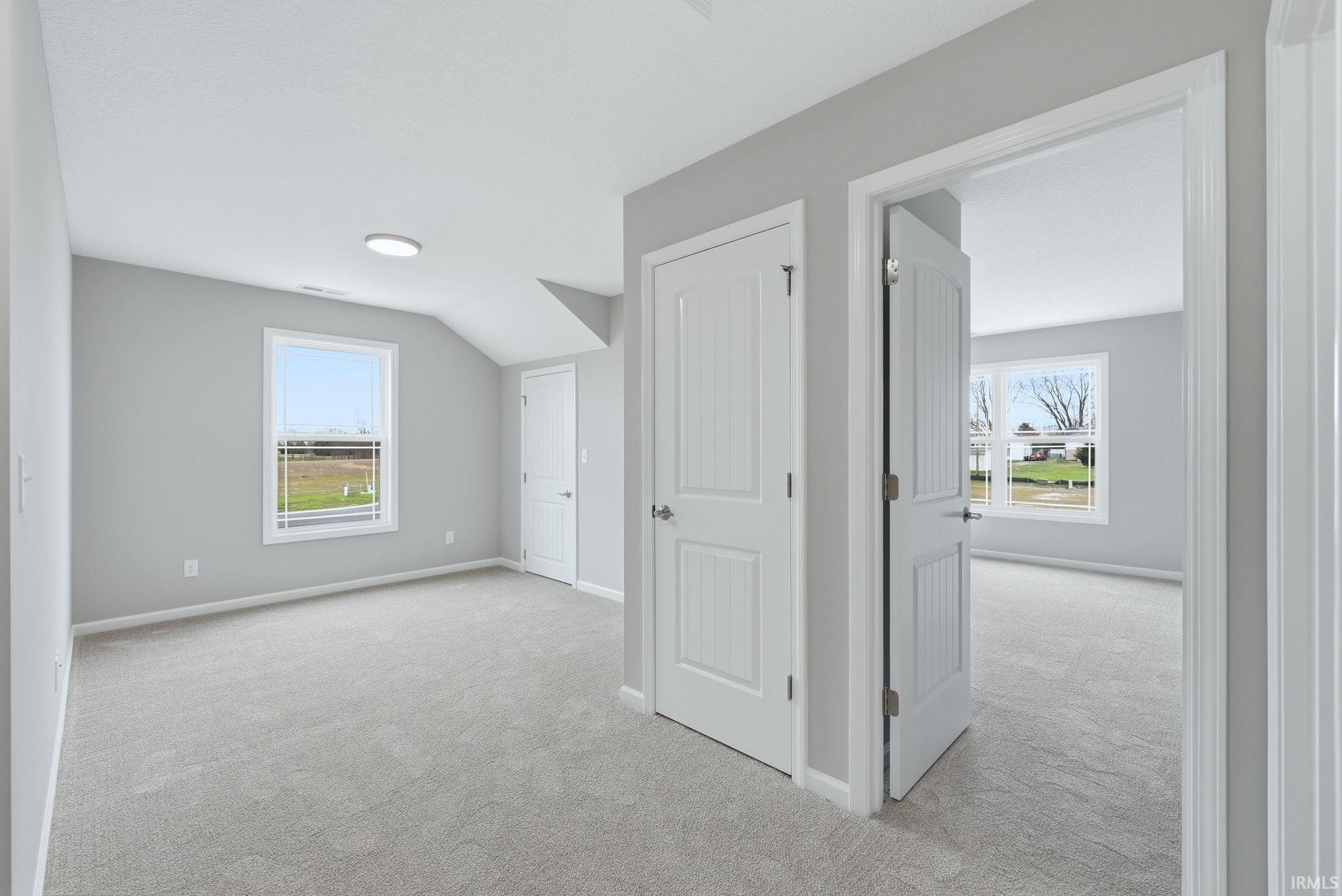 Additional living space with light carpet and baseboards
