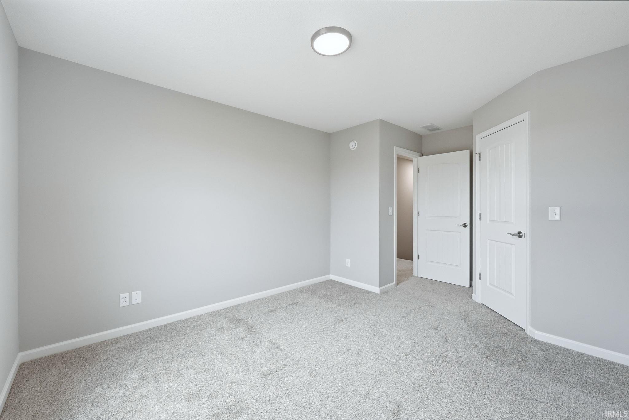 Unfurnished bedroom with baseboards and light colored carpet