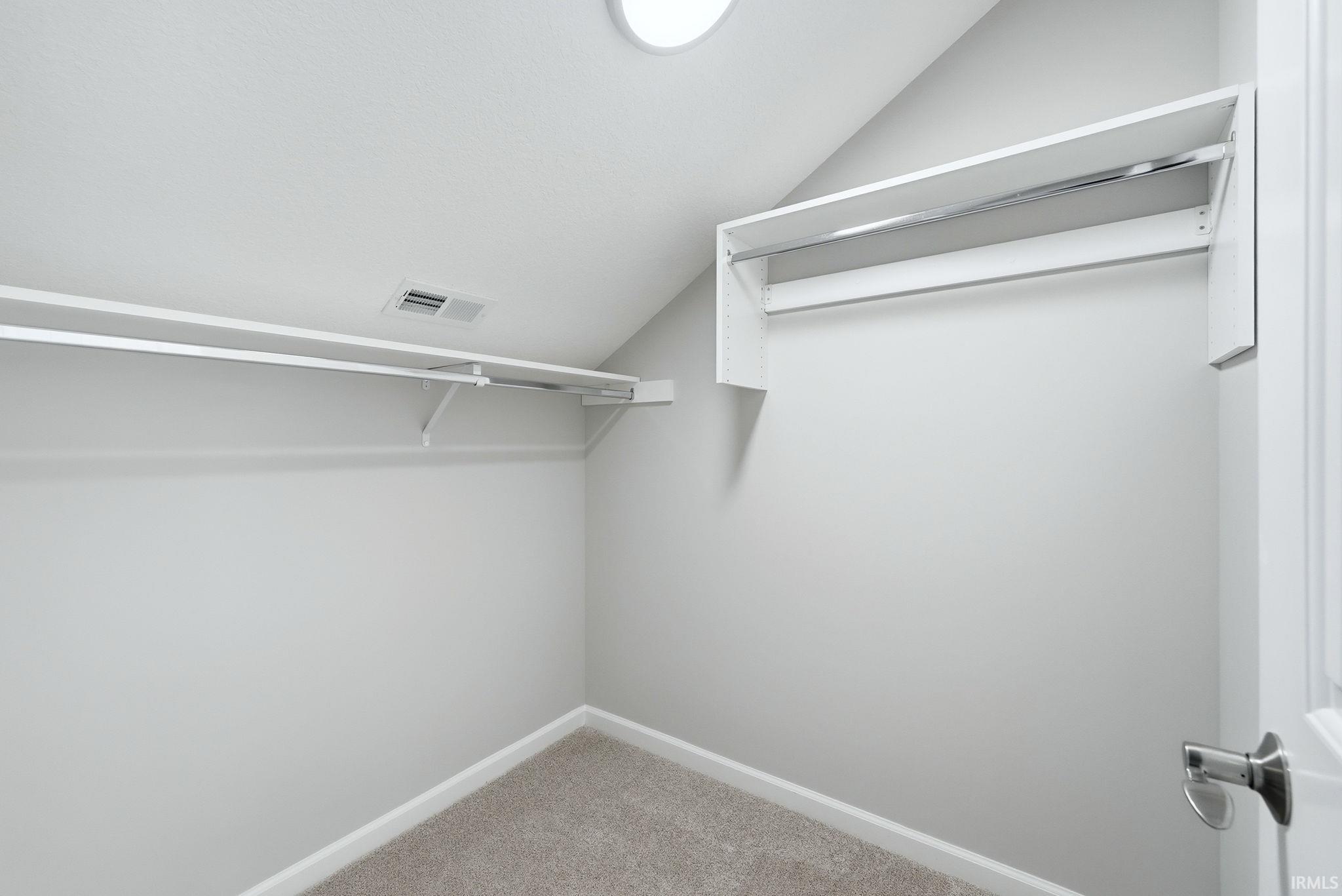 Walk in closet featuring vaulted ceiling and light colored carpet