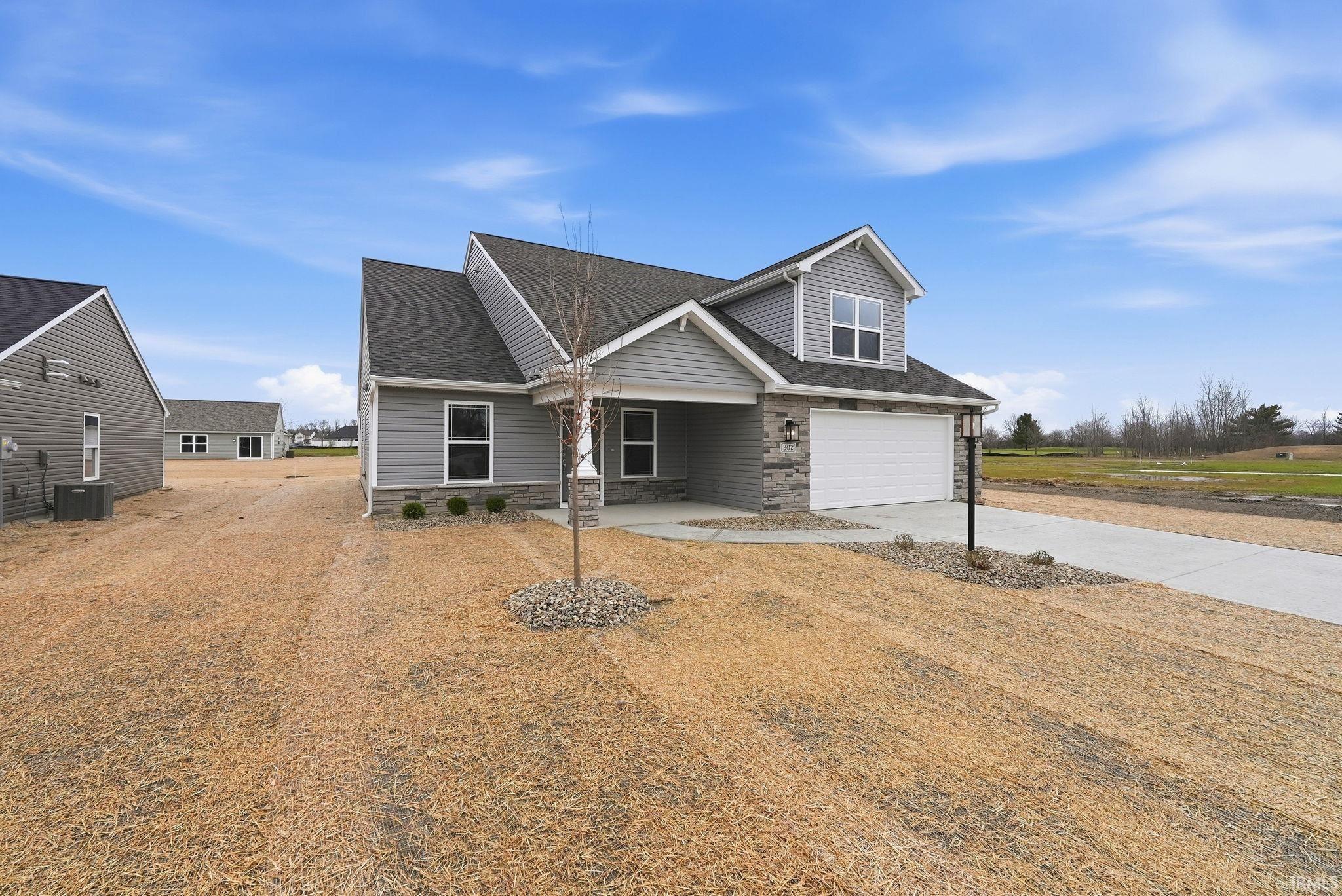 Traditional-style house featuring roof with shingles, driveway, stone siding, and an attached garage