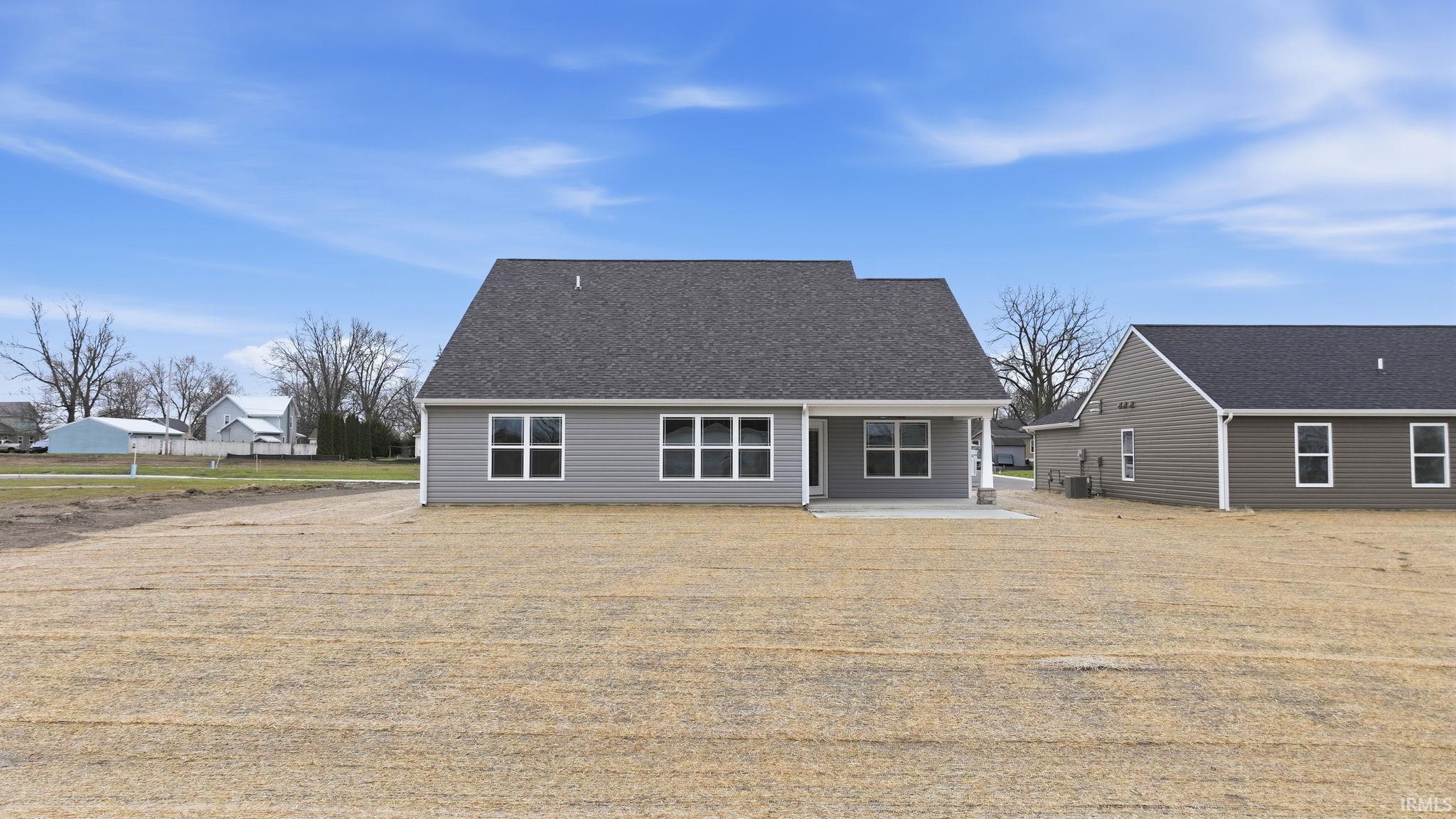 Rear view of house with a patio area and a shingled roof