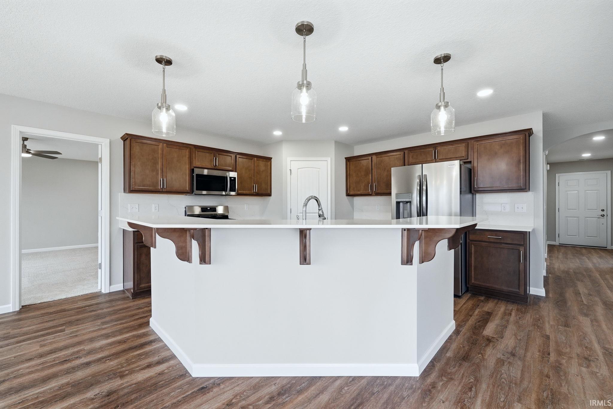 Kitchen with a kitchen bar, arched walkways, and decorative light fixtures