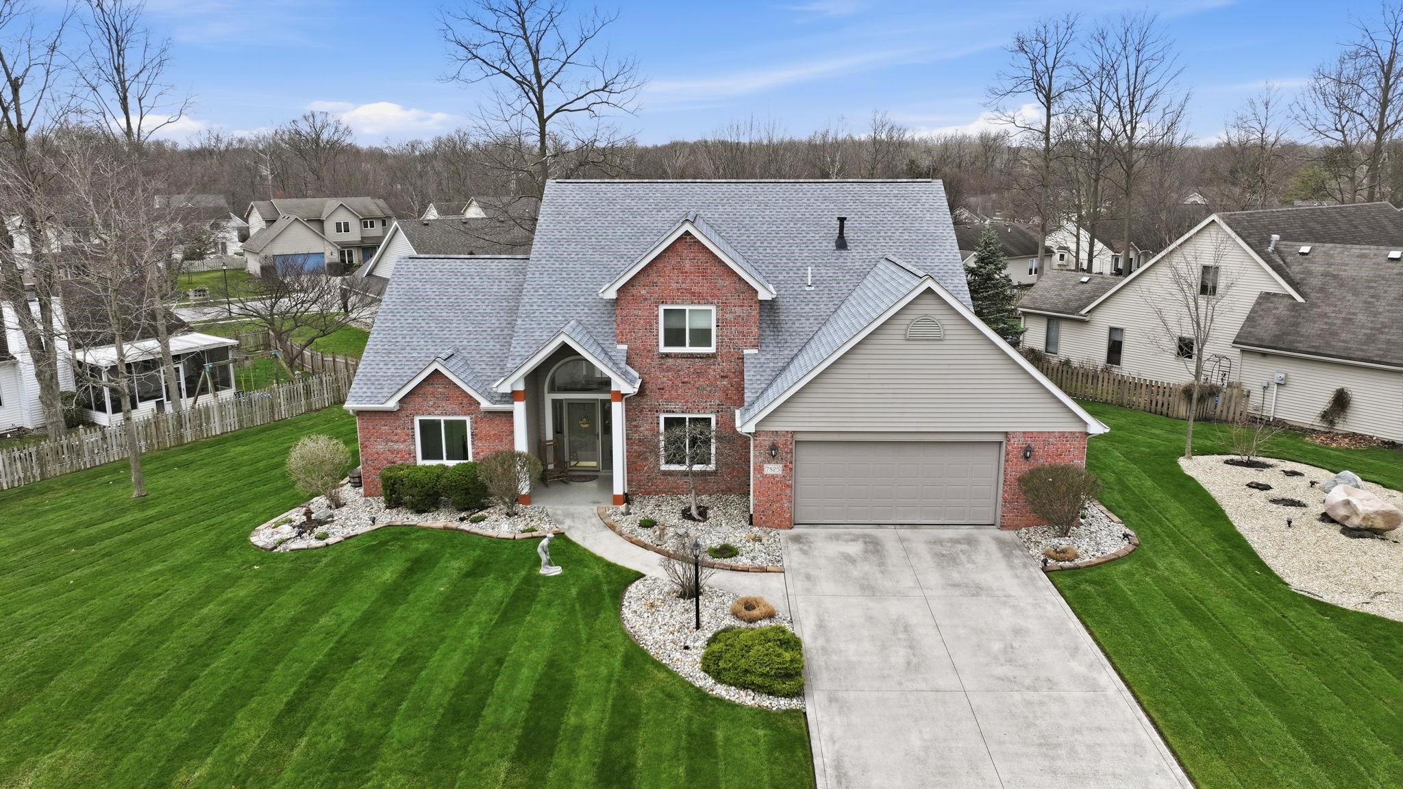Traditional-style home featuring brick siding, driveway, a garage, roof with shingles, and a residential view