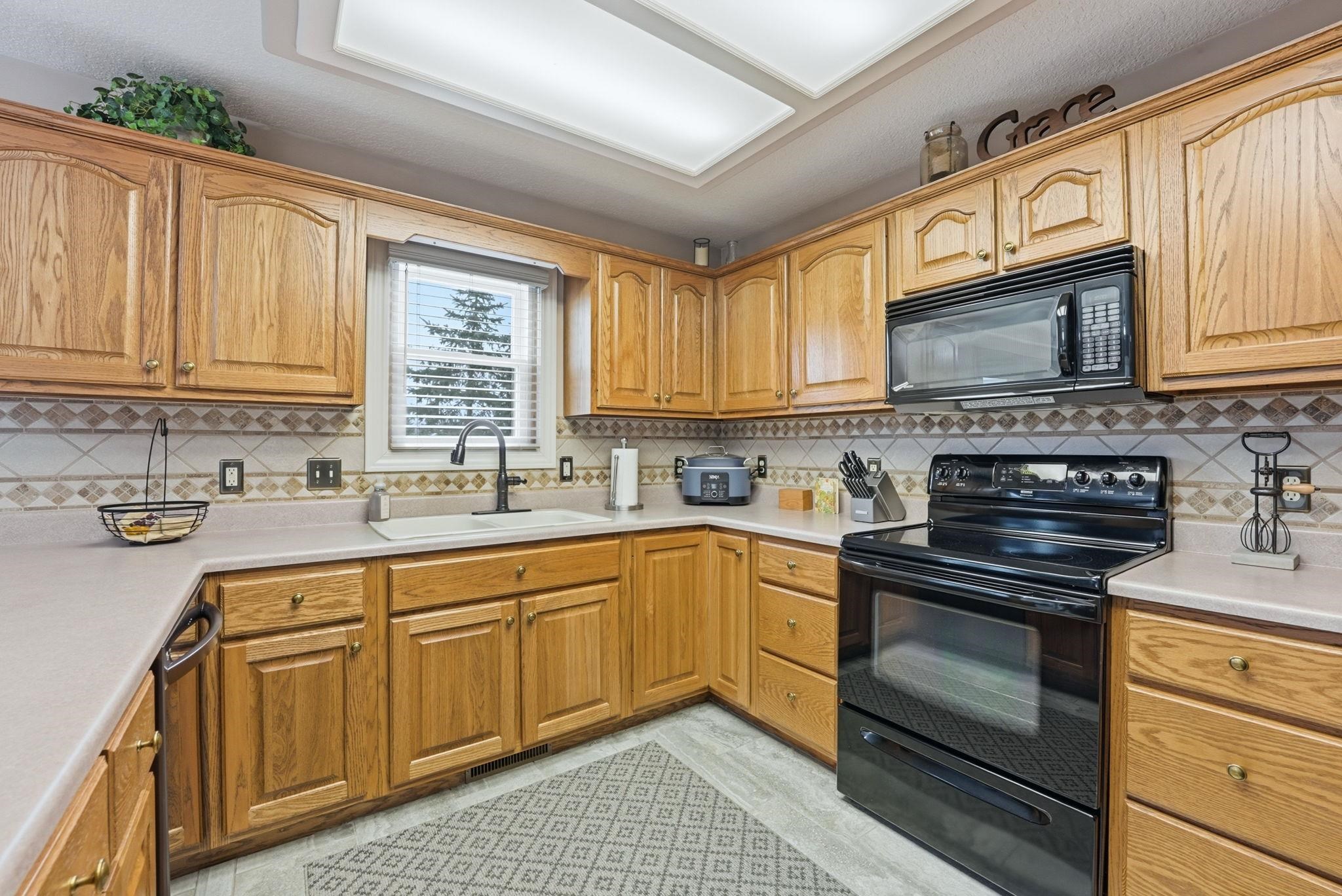 Kitchen with black appliances, light countertops, and wood finish cabinets