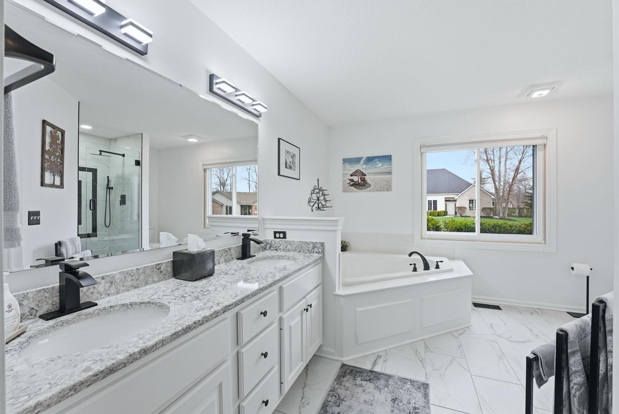 Bathroom with a stall shower, double vanity, a bath, and light marble finish flooring