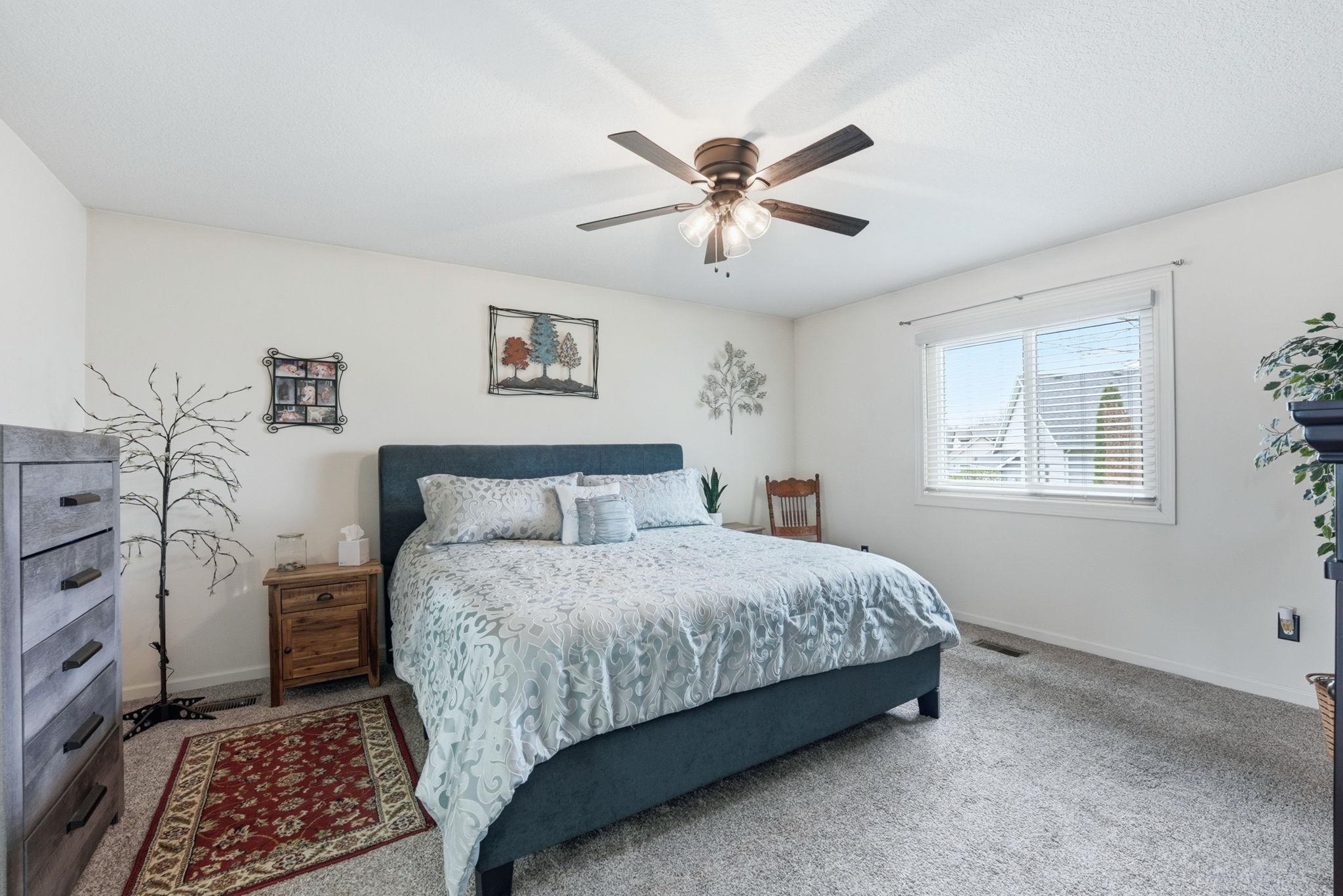 Carpeted bedroom featuring ceiling fan and baseboards
