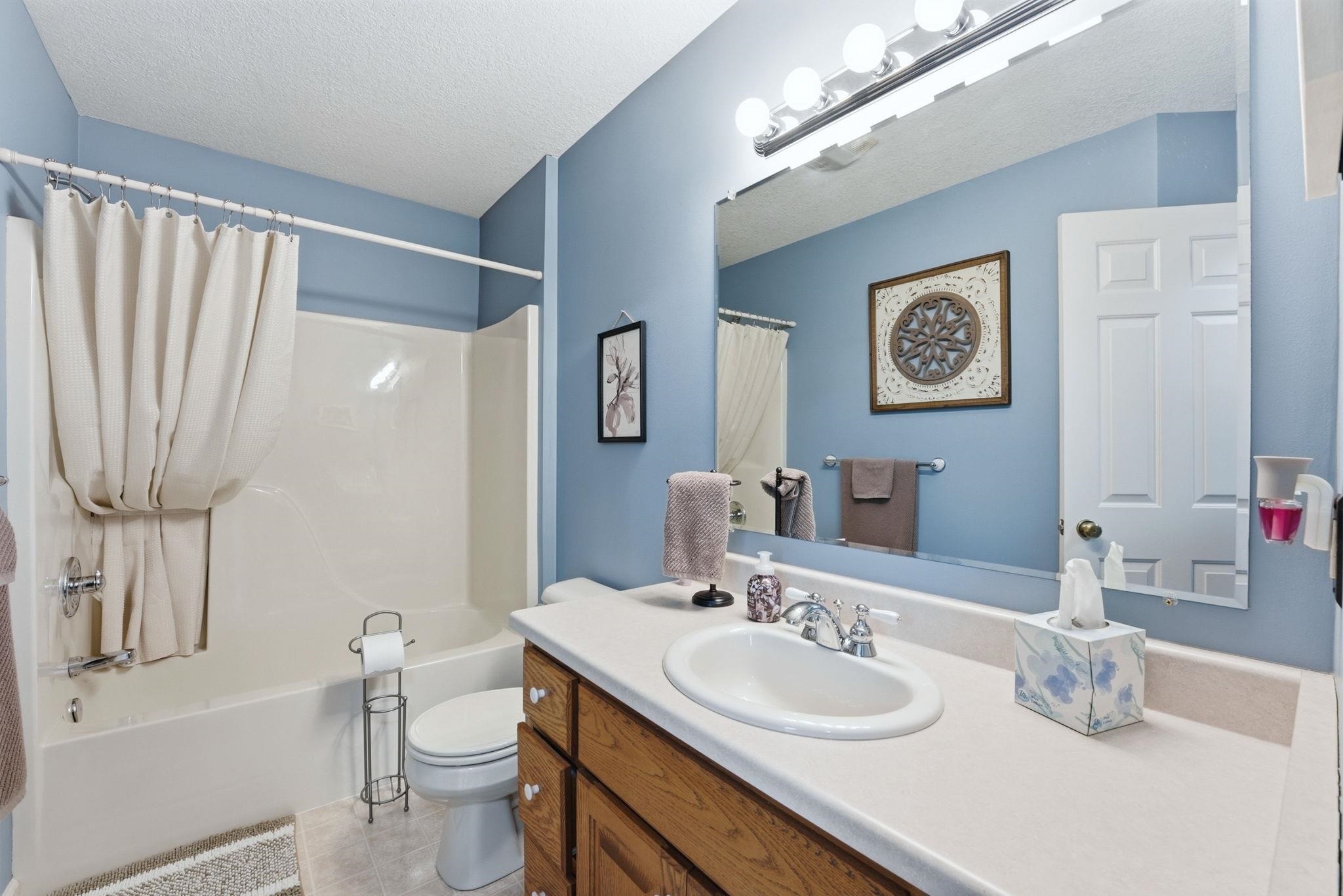 Full bath with vanity, shower / tub combo, and a textured ceiling