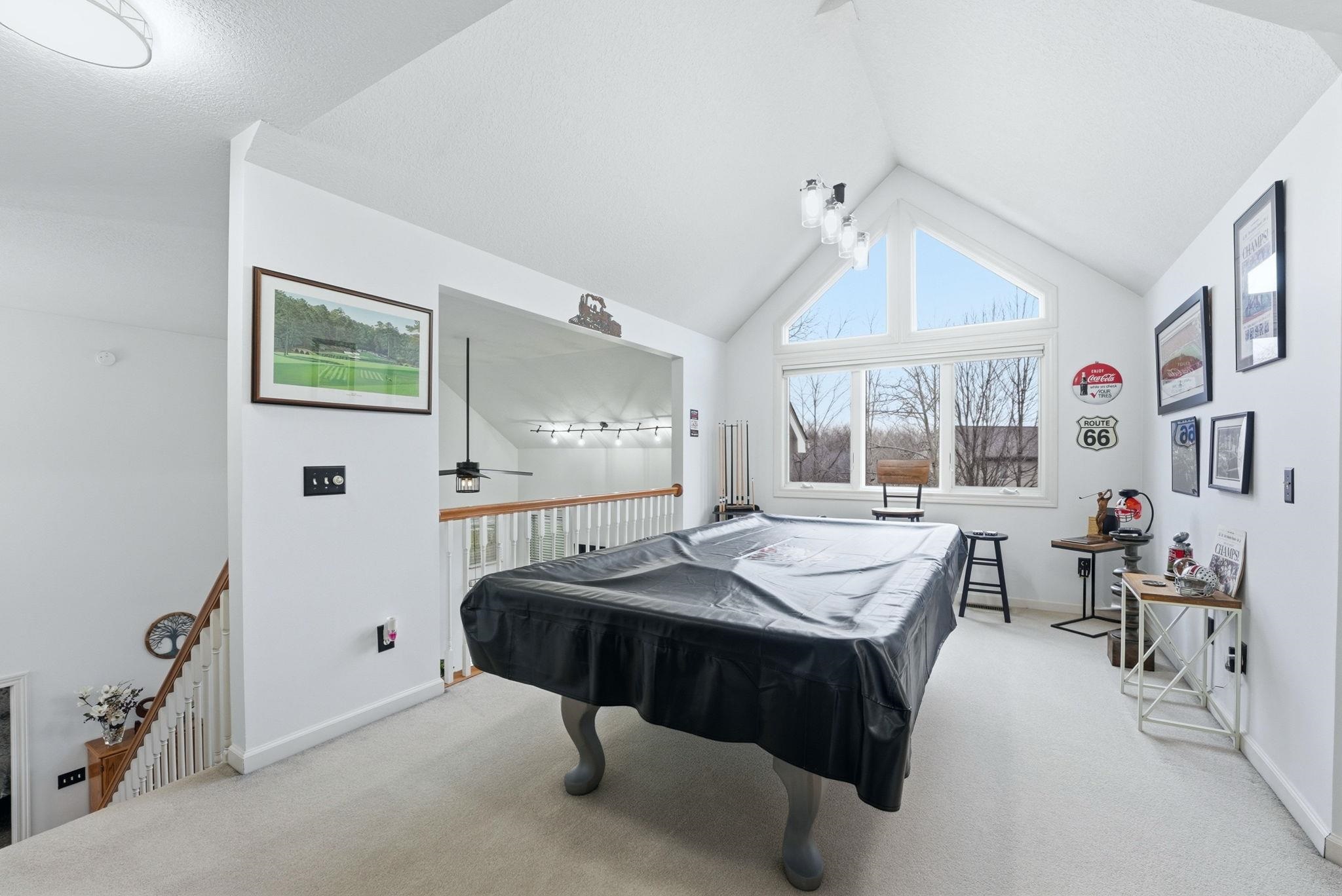 Game room with pool table, light carpet, ceiling fan, and a high ceiling