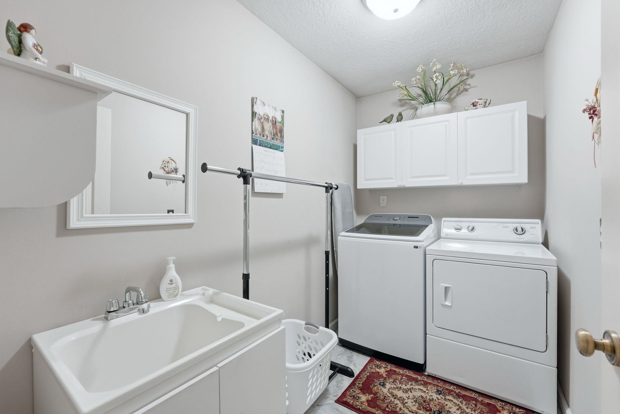 Laundry room featuring a textured ceiling, washer and clothes dryer, and cabinet space
