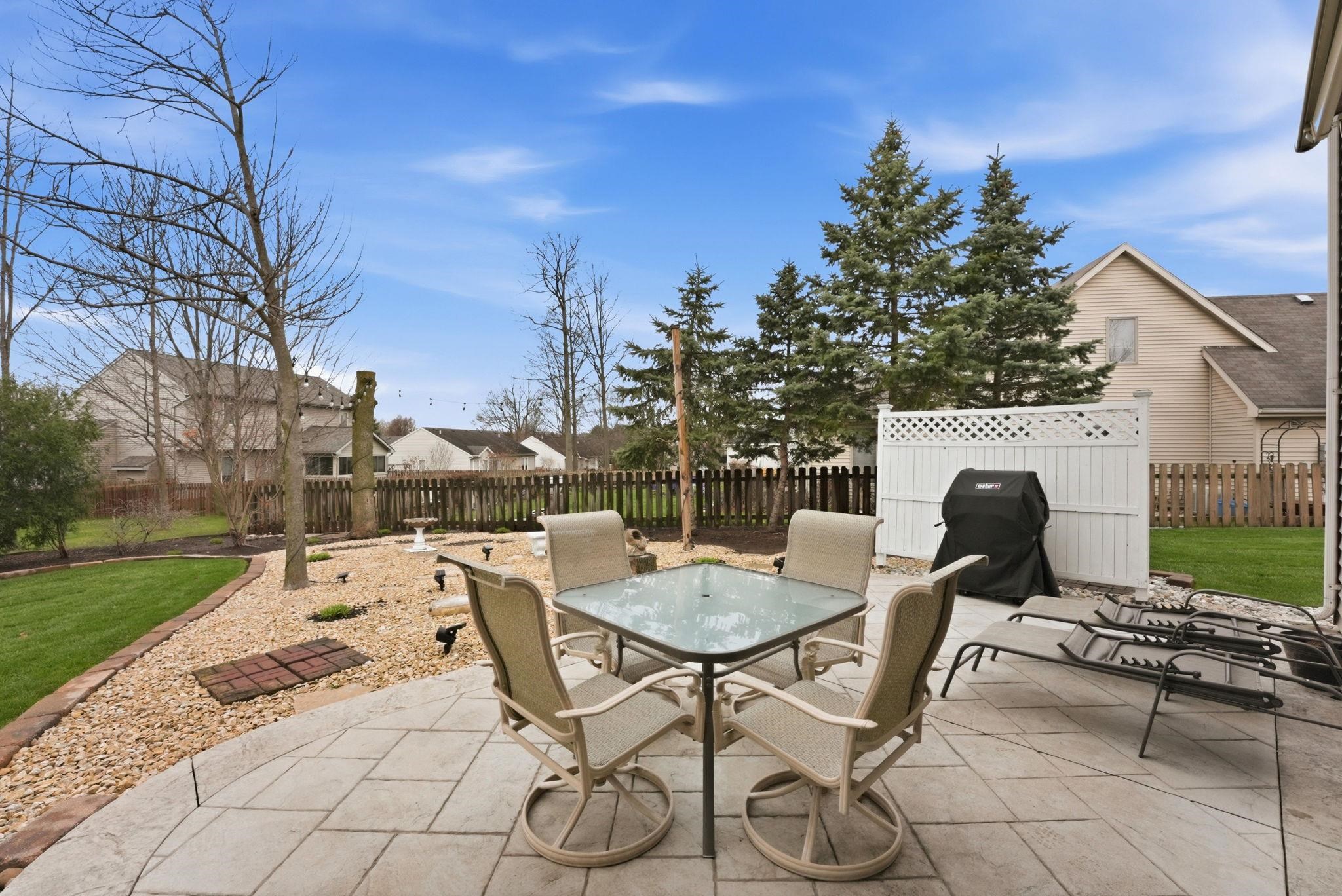 Fenced backyard with outdoor dining area, grilling area, and a patio area