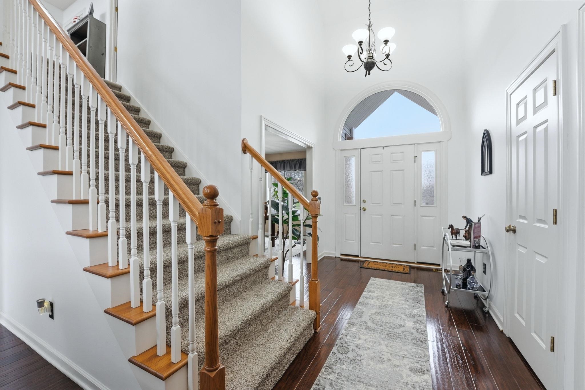 Entrance foyer featuring dark wood finished floors, a chandelier, and a high ceiling