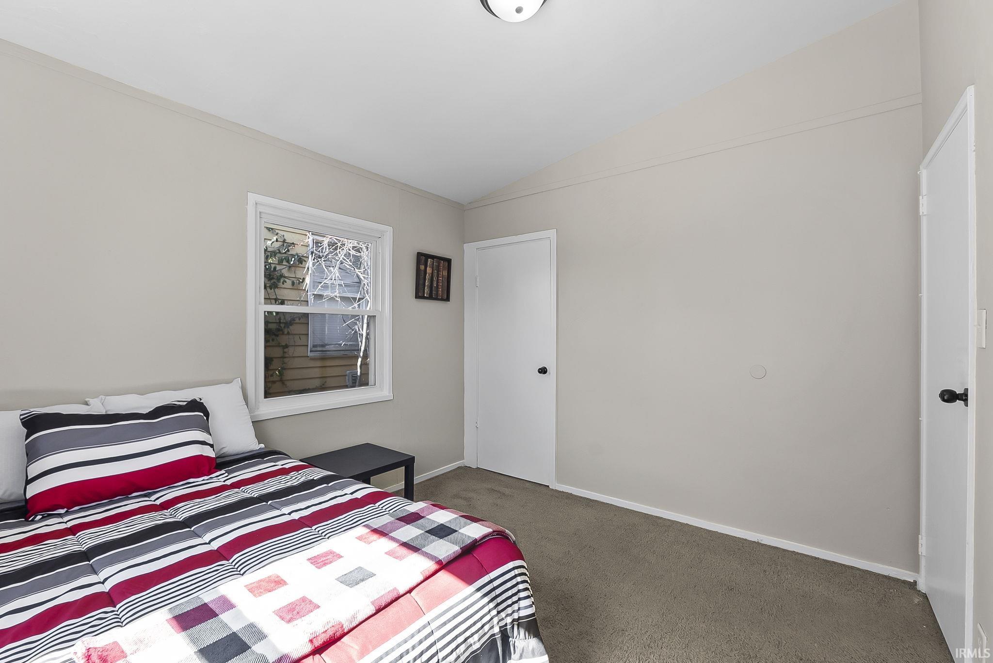 Carpeted bedroom with lofted ceiling and baseboards