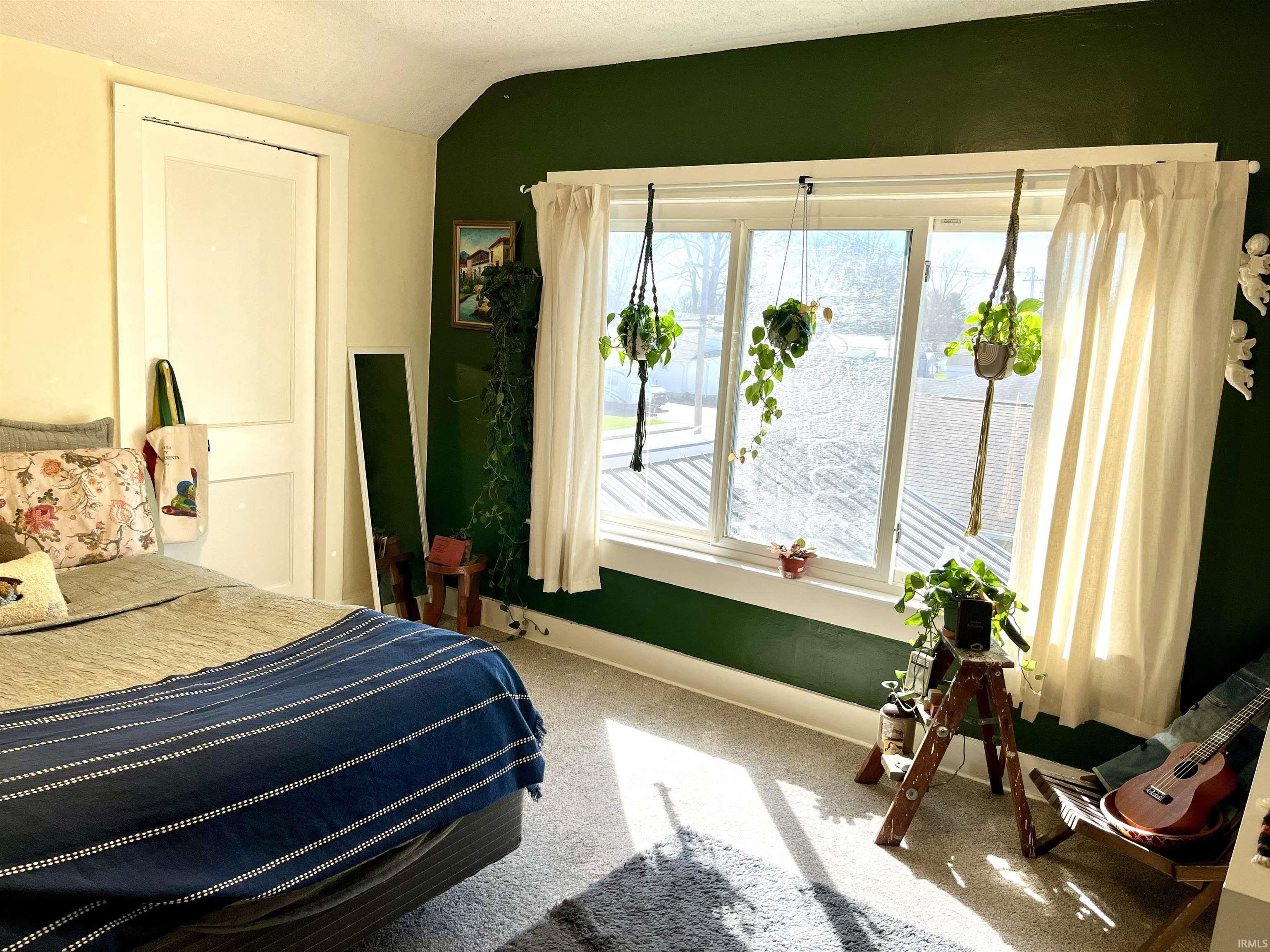 Bedroom with vaulted ceiling and light carpet