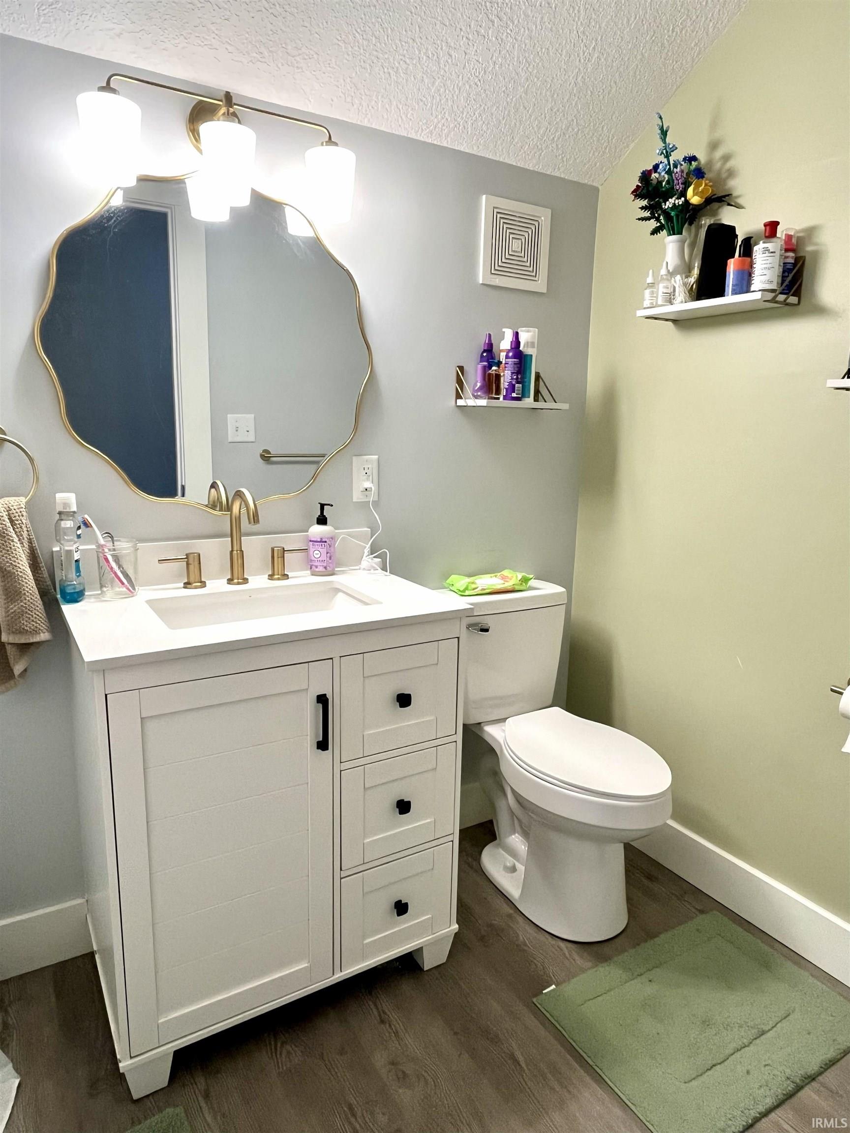 Bathroom featuring vanity, a textured ceiling, and dark wood-type flooring