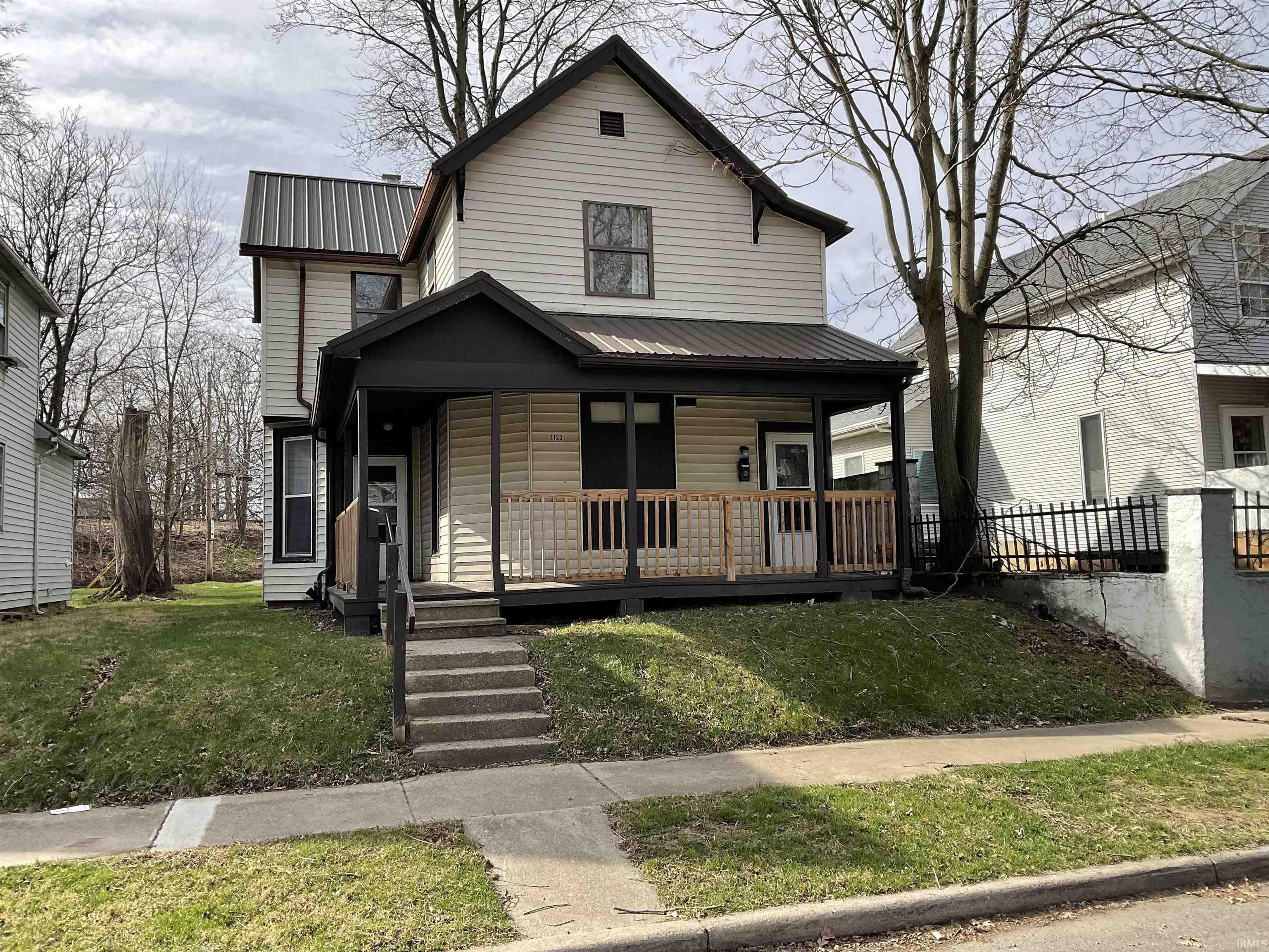 View of front of home with a metal roof, a porch, and a front lawn