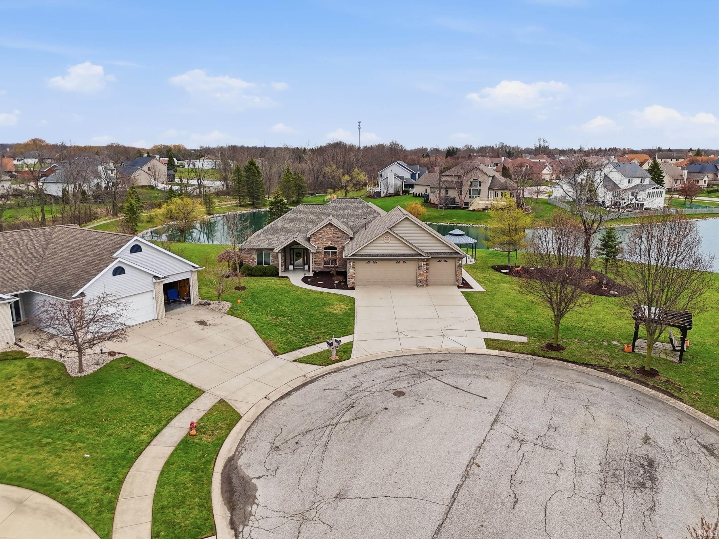 View of front of property with a residential view, concrete driveway, a front yard, a garage, and a water view