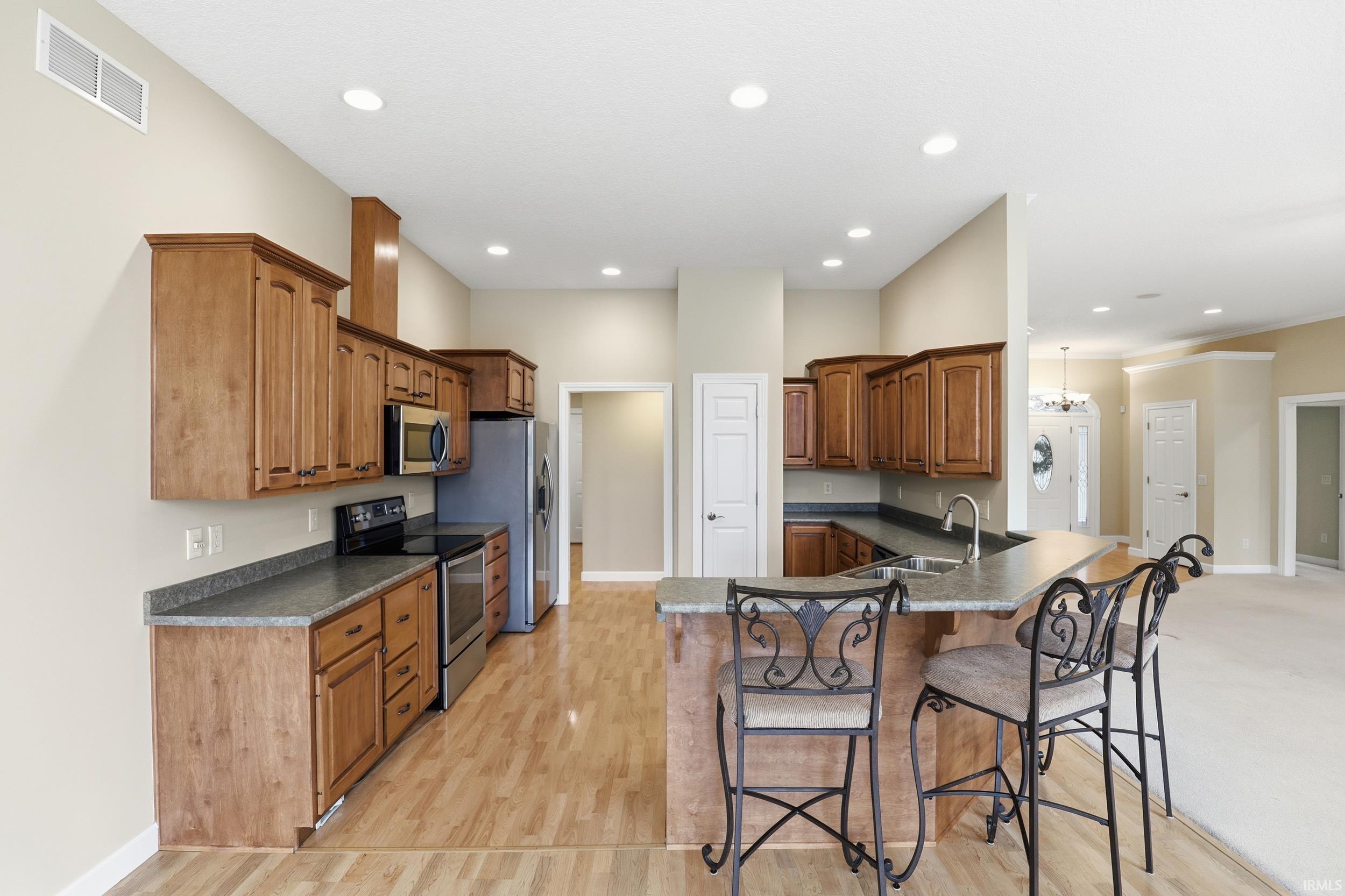 Kitchen with wood finish cabinets, a breakfast bar, stainless steel appliances, and dark countertops